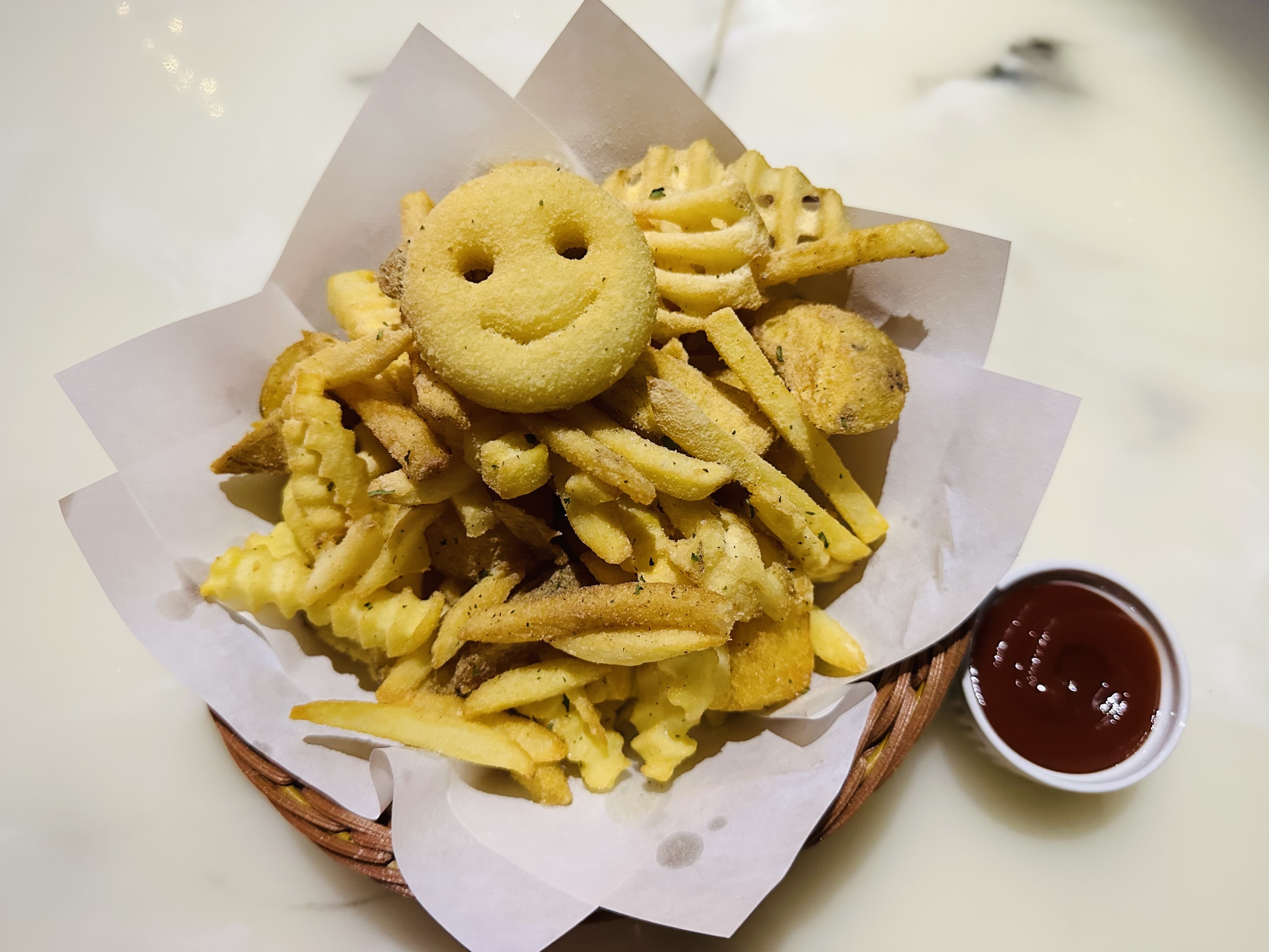 Basket of golden crispy fries and smiley potatoes with ketchup