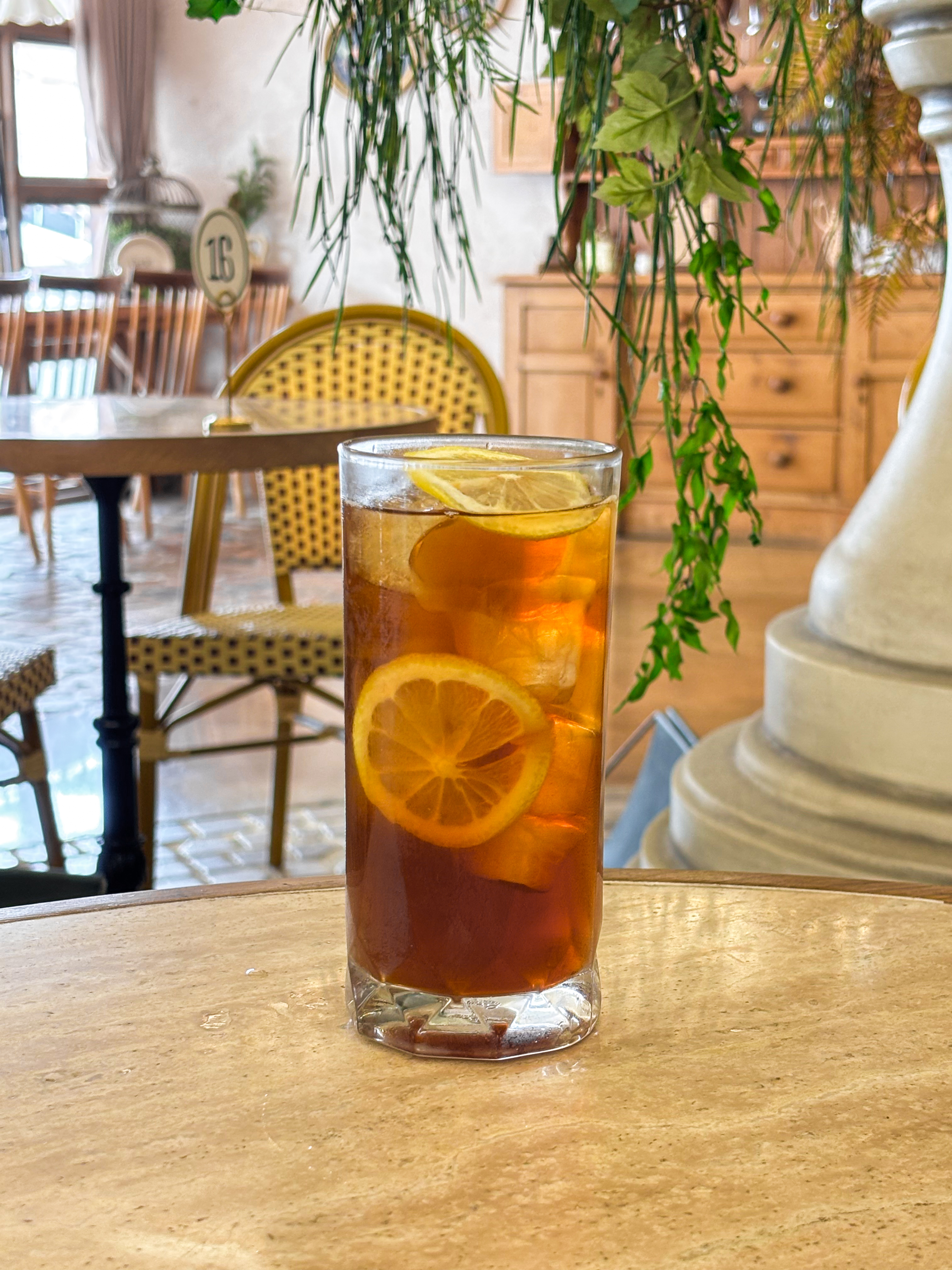 A glass of iced lemon tea on a stone table inside a cafe