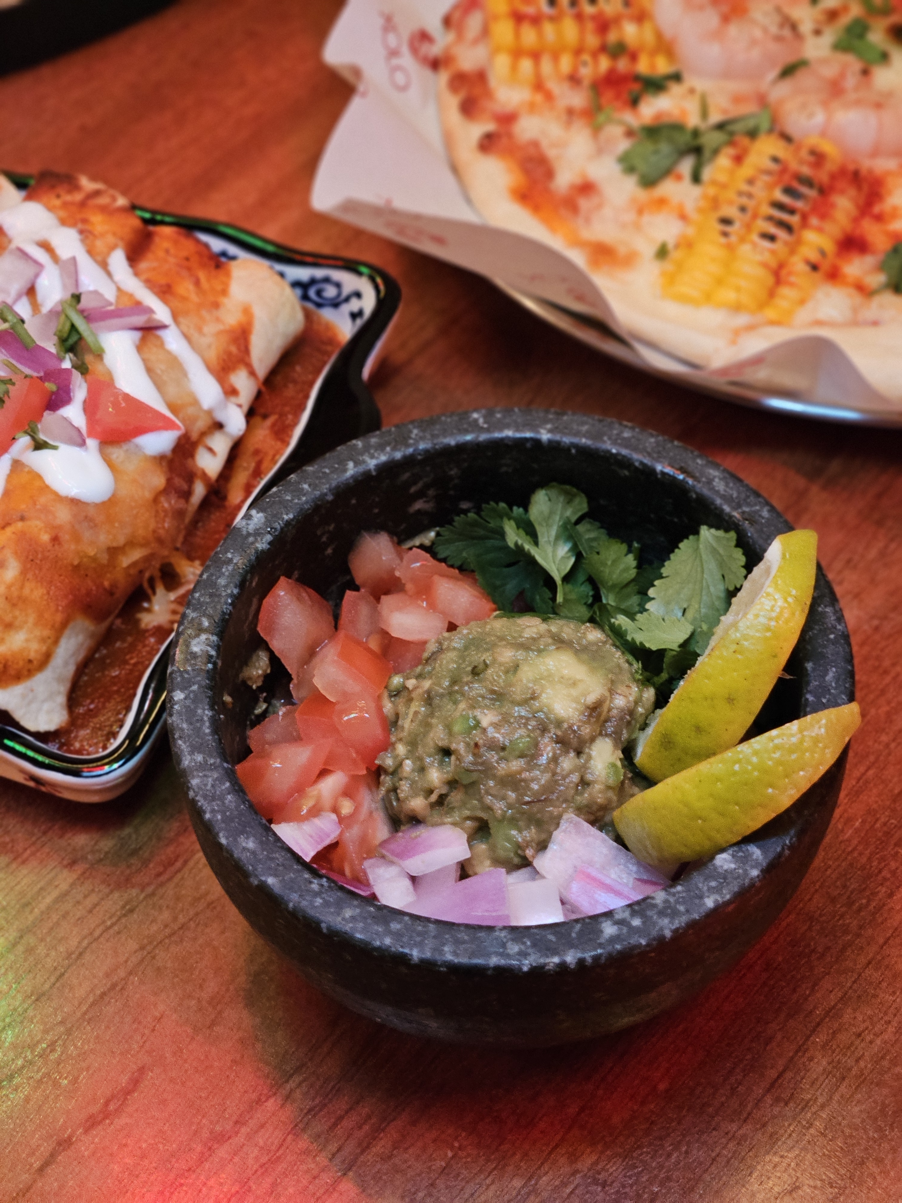 Fresh guacamole in a traditional stone bowl with diced tomatoes, onions, and limes