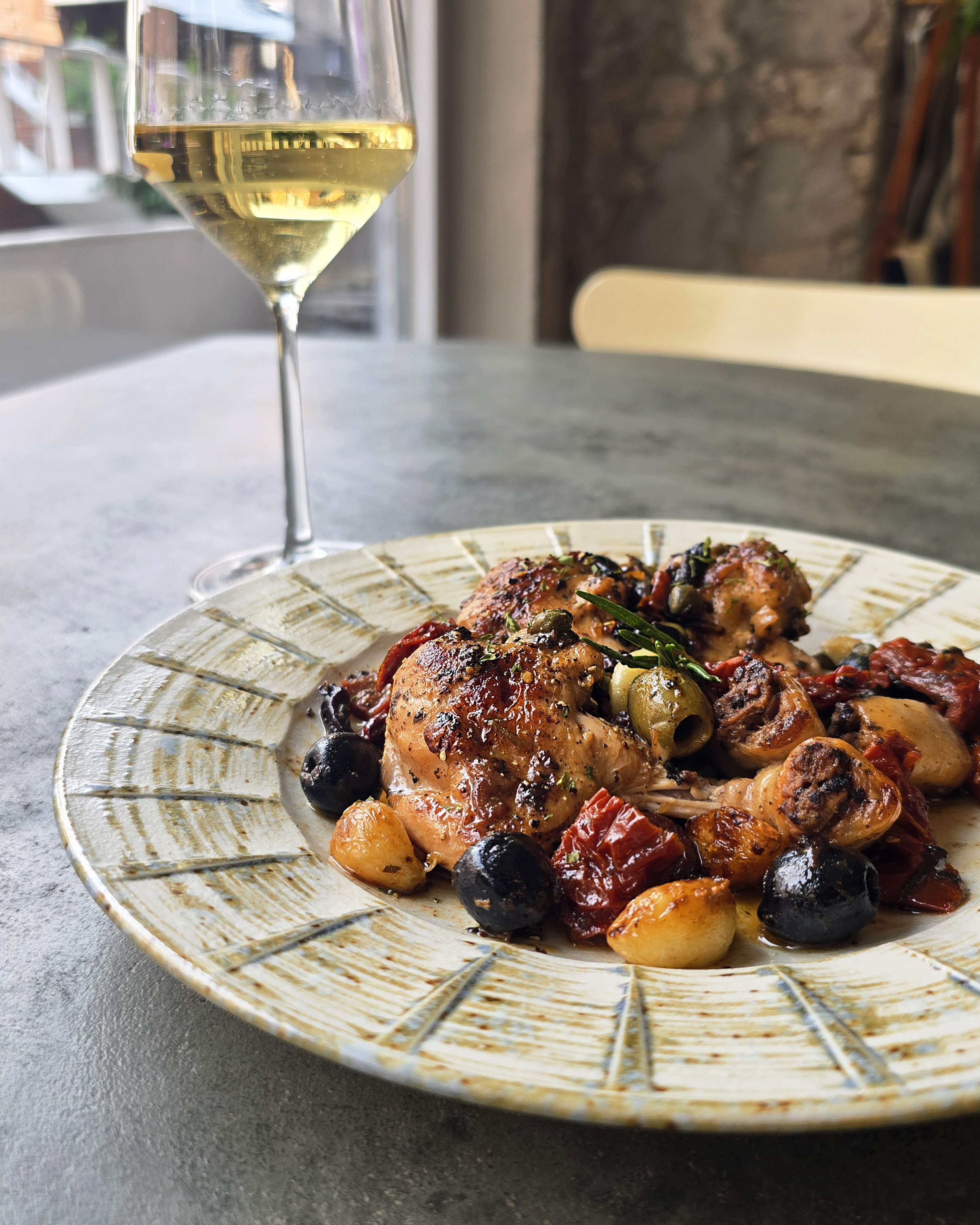Roasted chicken with olives and sun-dried tomatoes paired with chilled white wine
