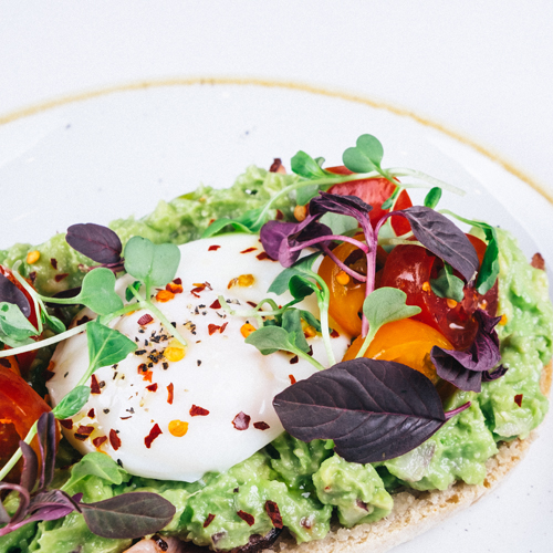 Close-up of avocado toast with poached egg and microgreens