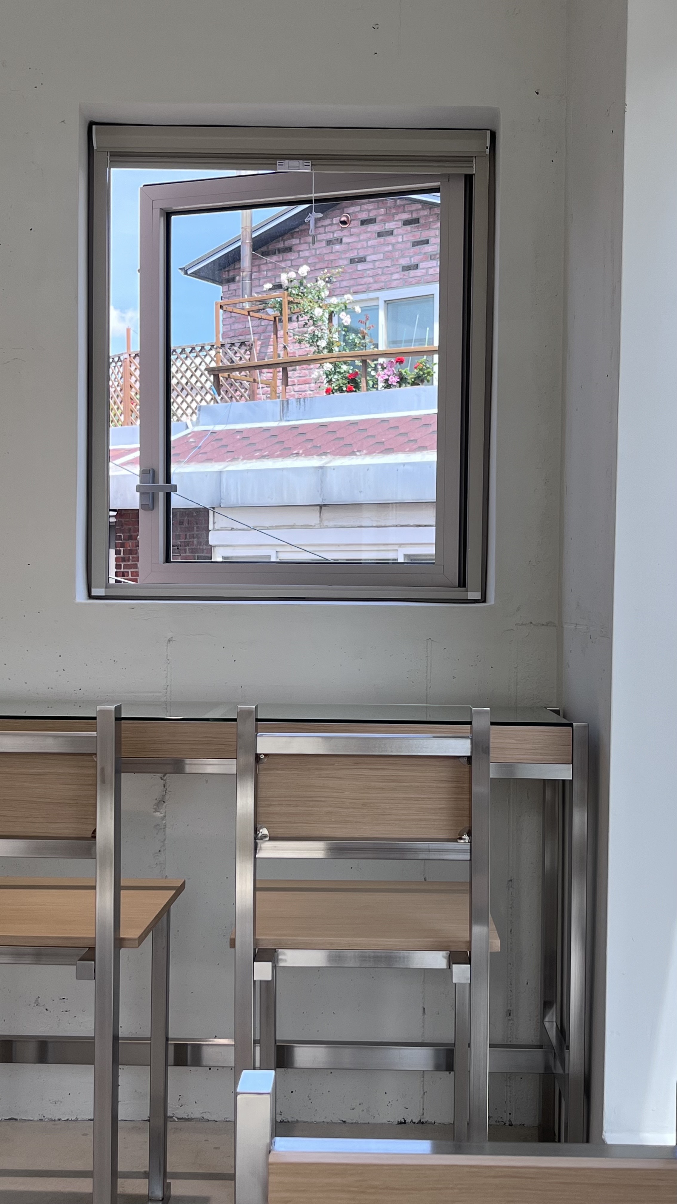 A window view looking out from an indoor studio space towards a brick building in Yeonnam-dong.
