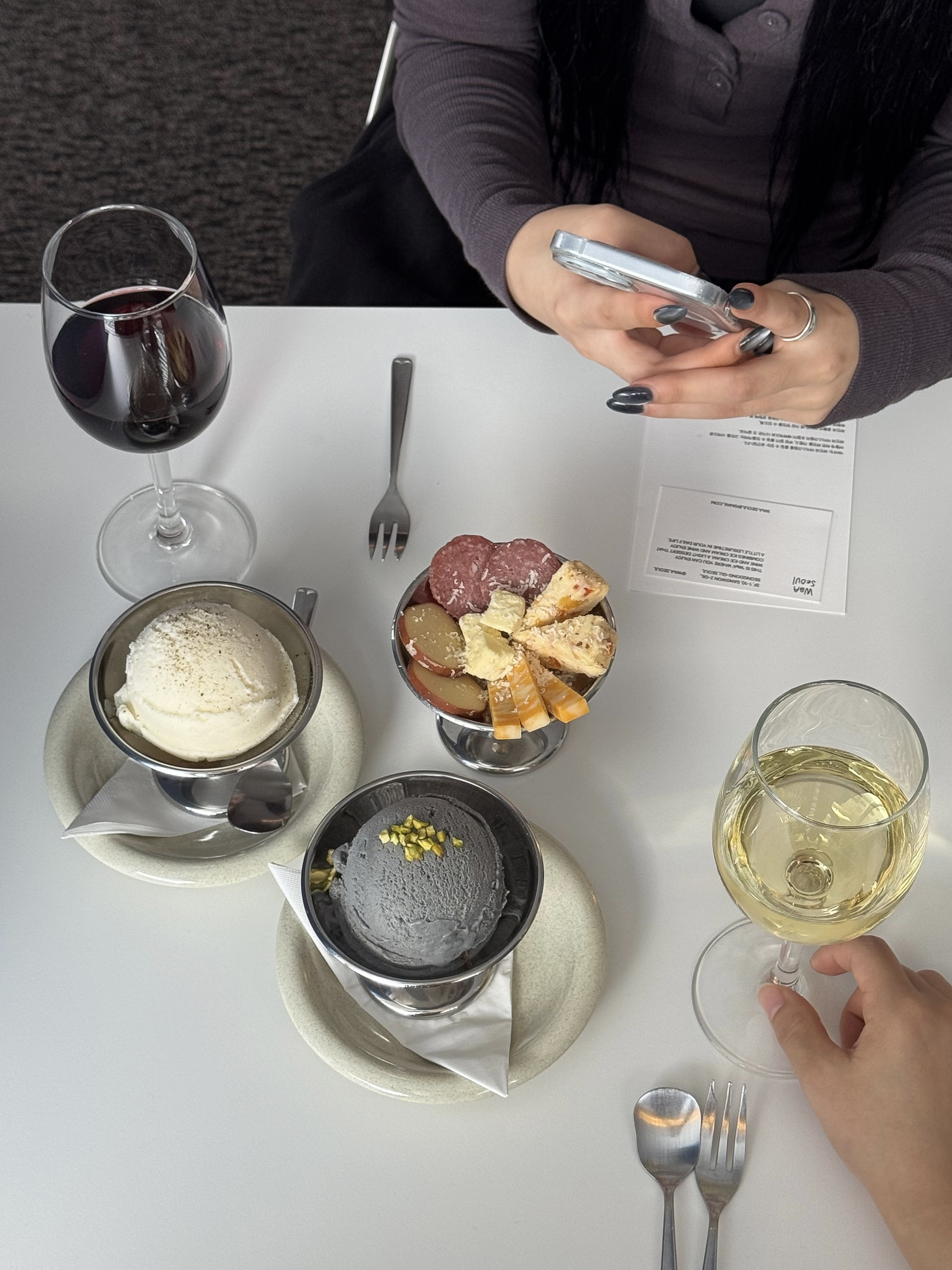 Table setting at Waa featuring red wine, white wine, artisanal ice cream in metallic bowls, and charcuterie