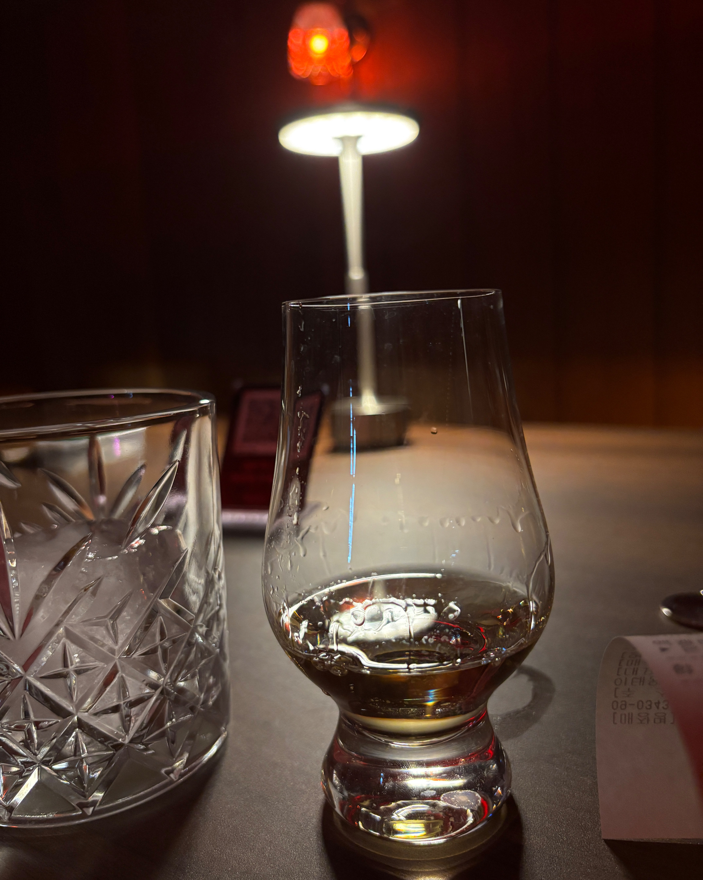 Tasting glass with amber spirit under low lighting at Blending Bar