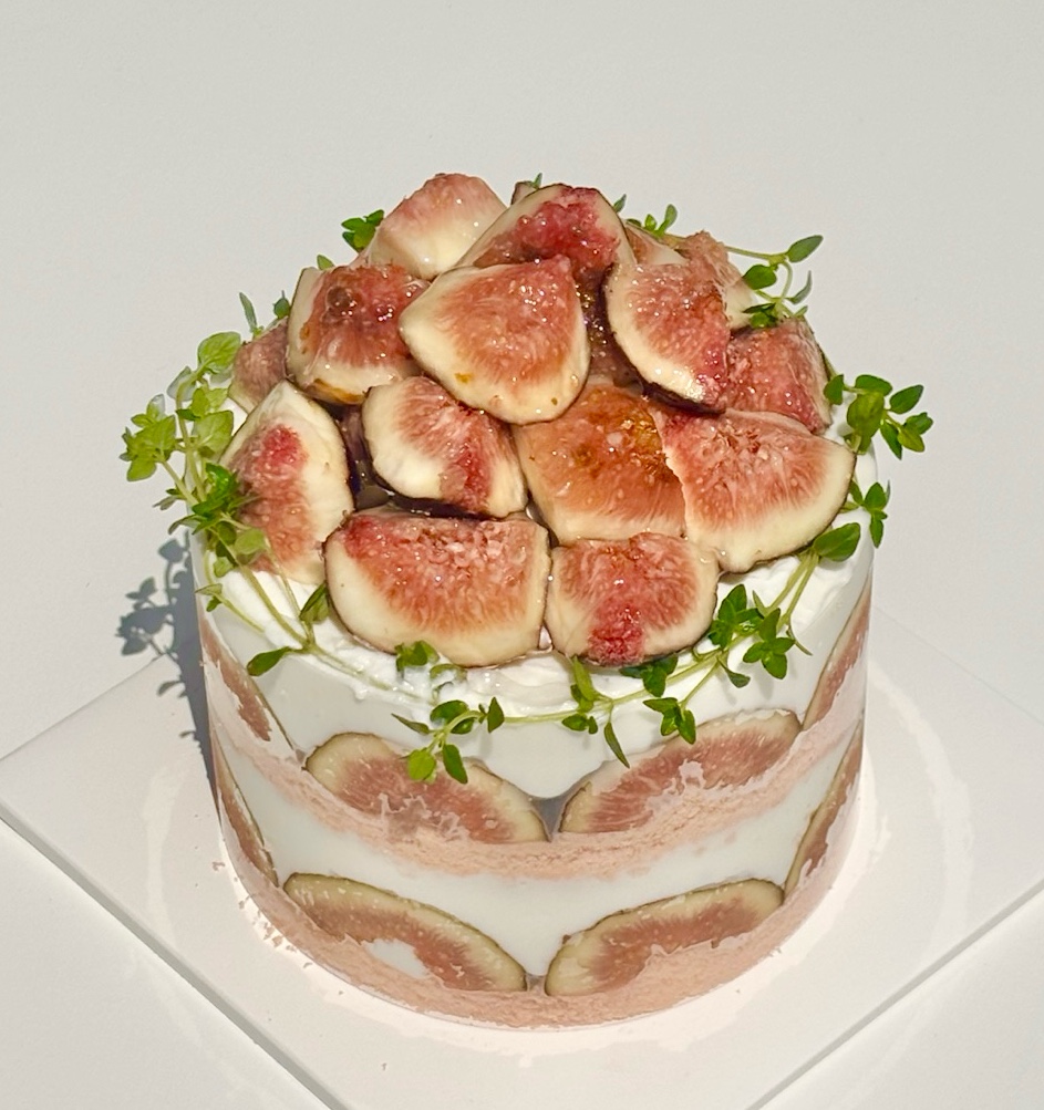 Round fig cake with thyme sprigs on square plate