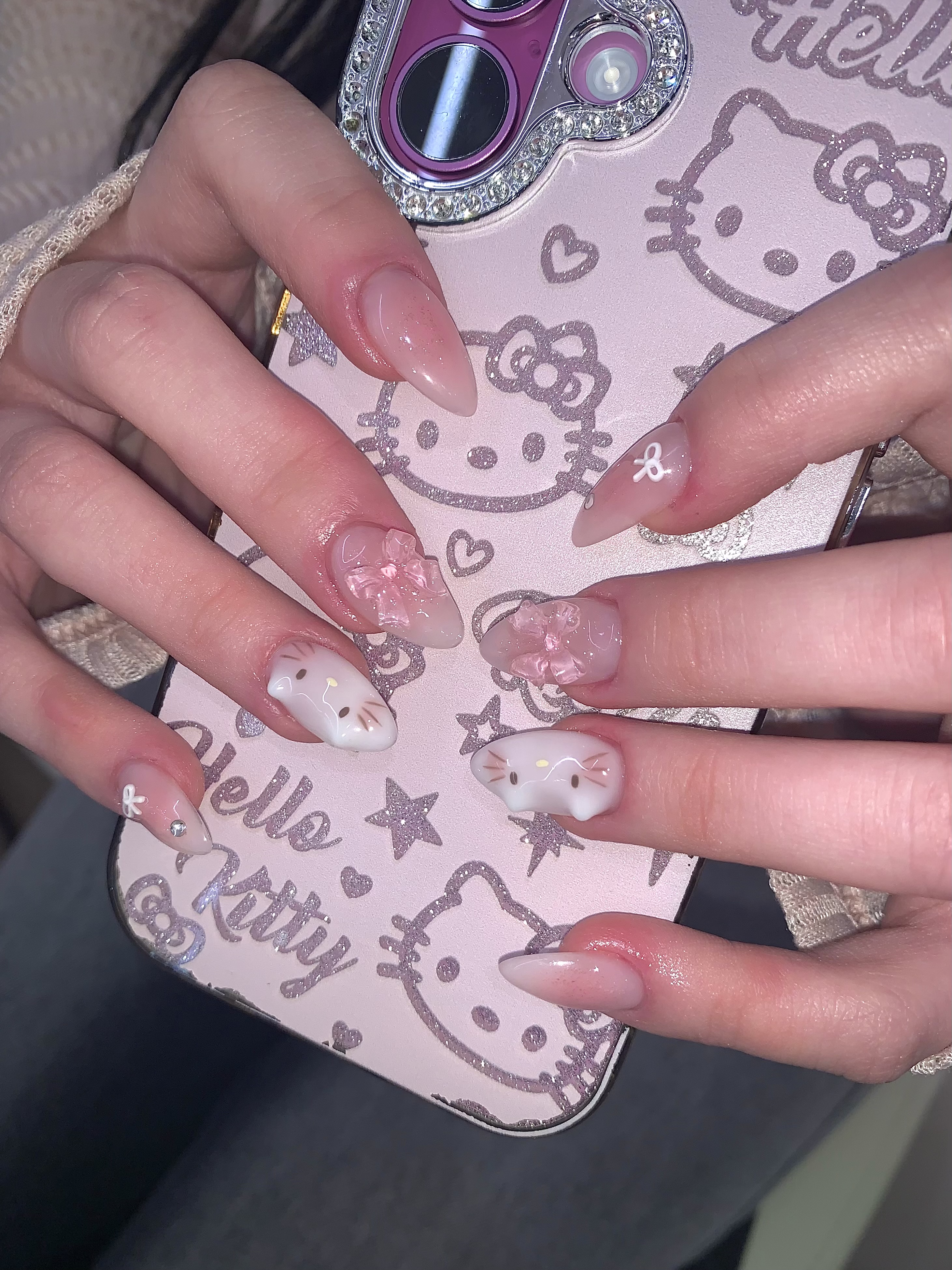 Close-up of hands with character-themed 3D nail art holding a pink smartphone case