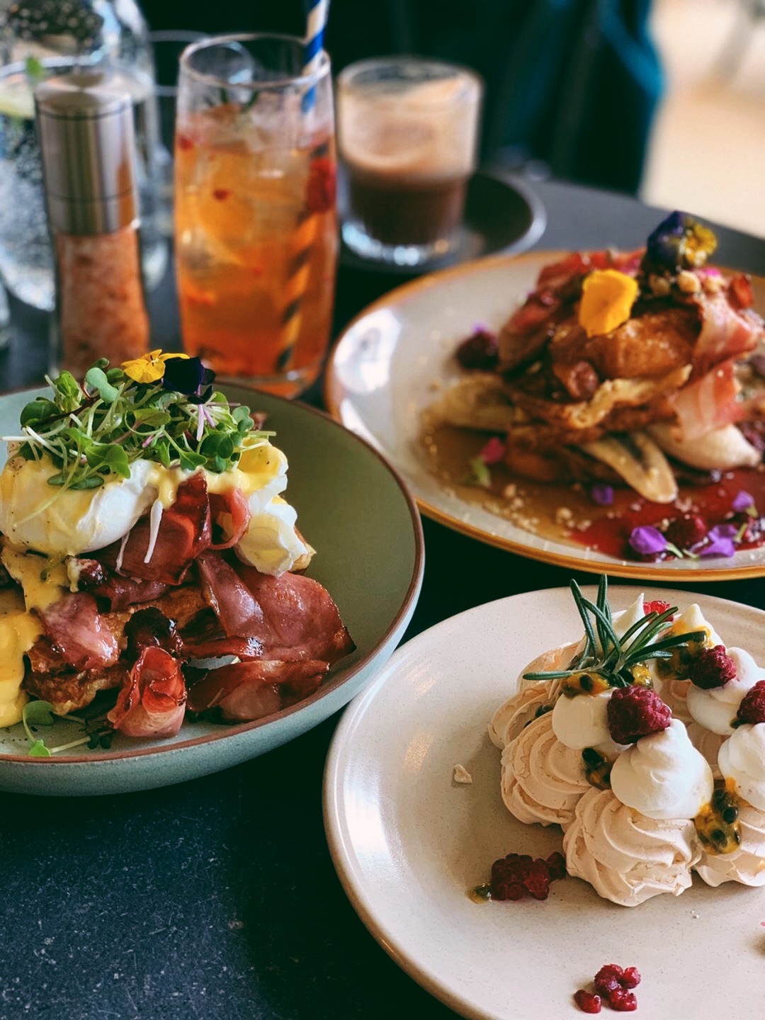 Three brunch plates and two drinks on a dark table at Summer Lane restaurant.