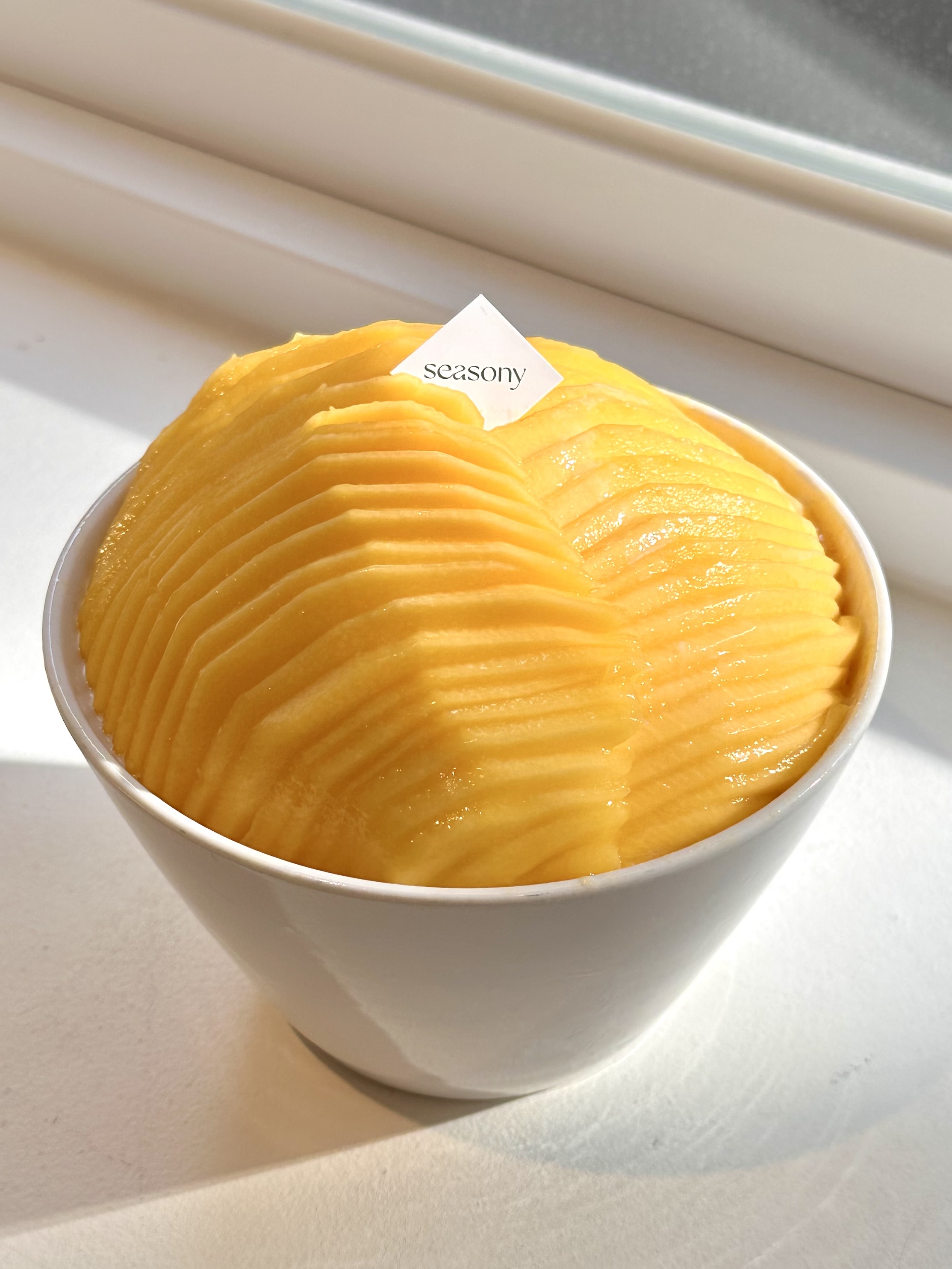 Top-down view of freshly prepared mango dessert bowl illuminated by sunlight