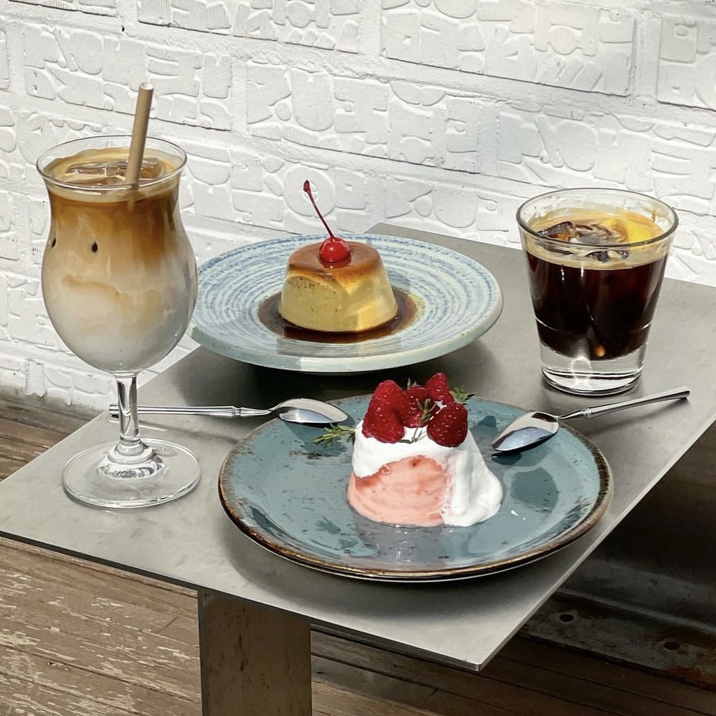 Table setting with iced latte, pudding, and cake on metallic table