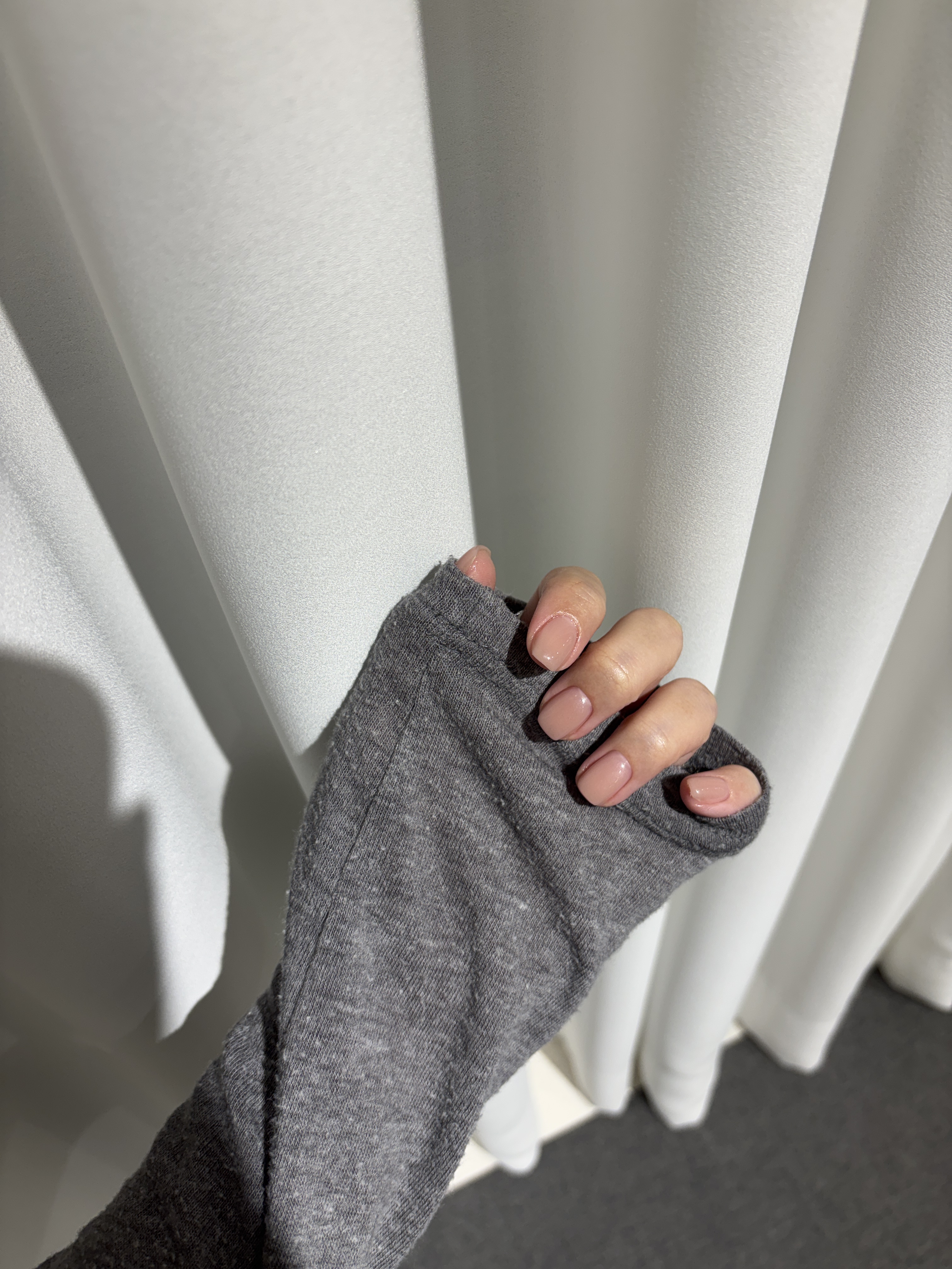 Short, clean fingernails painted in glossy nude beige polish