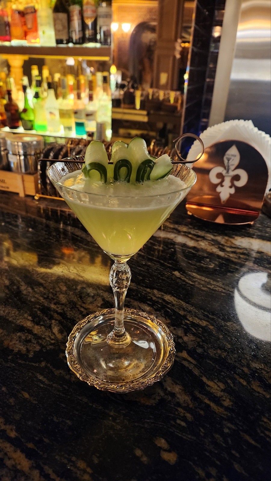 Handcrafted cocktail with fresh cucumber garnish in a stemmed crystal glass