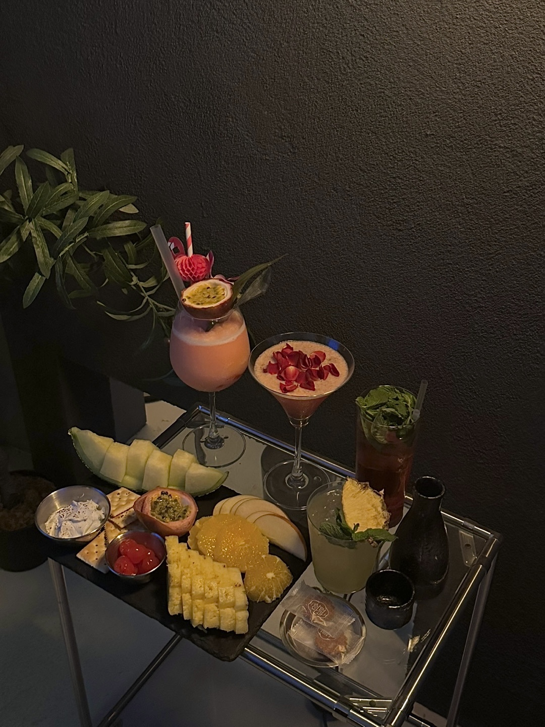 Bar cart service with cocktails, sliced melon, pineapple, and fresh snack platters