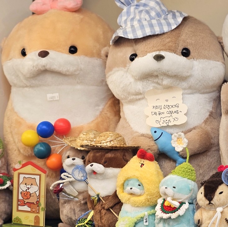Sea otter plushies wearing checkered hats and straw hoods at Gleaming Day
