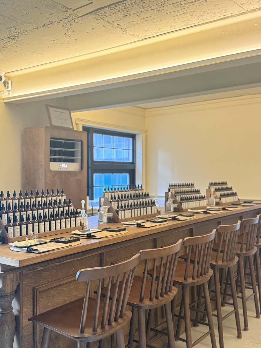 Warm timber workshop counter and wooden stools lined with fragrance formulation stations