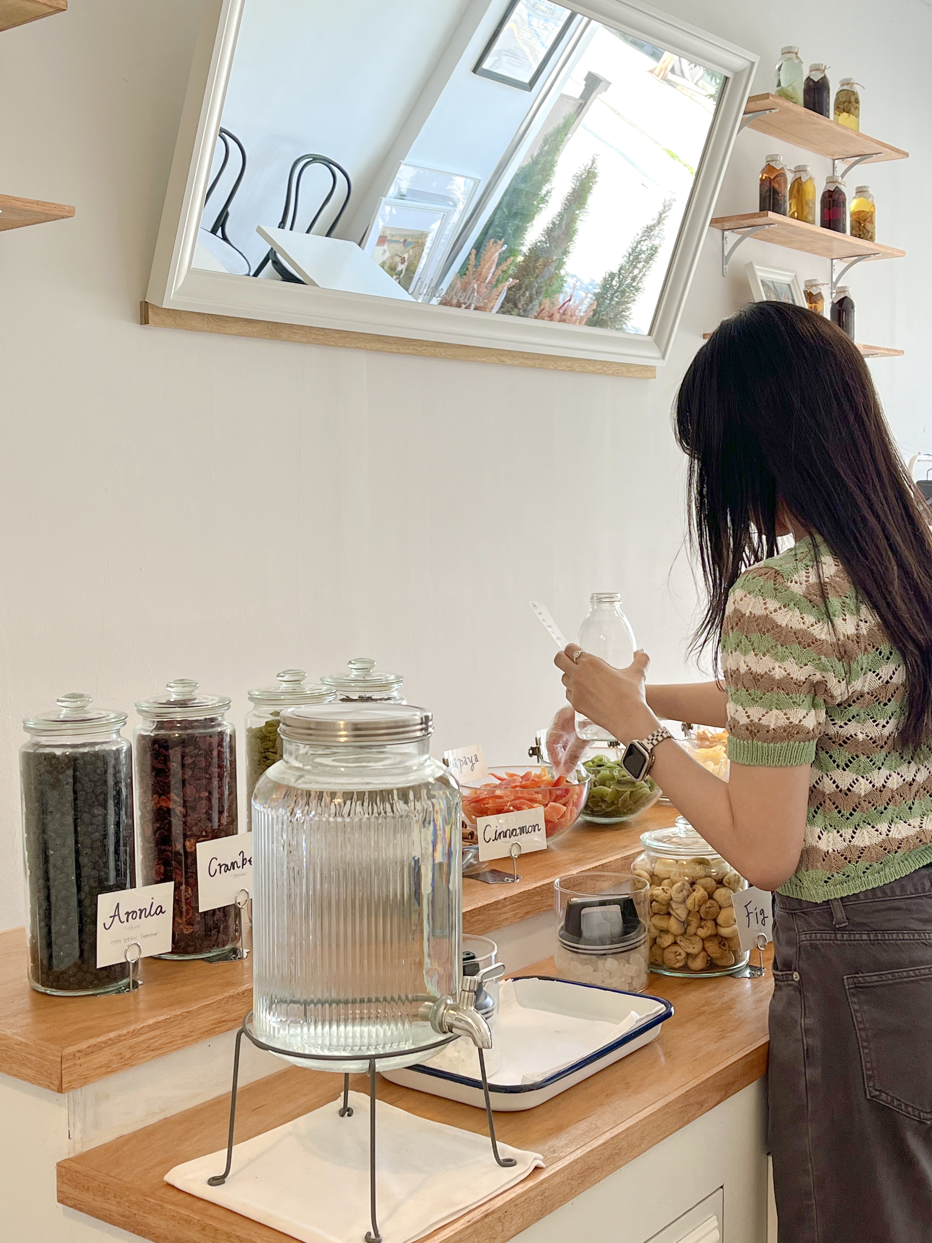Visitor preparing infused botanical alcohol ingredients at a wooden counter at Uuhee Atelier.