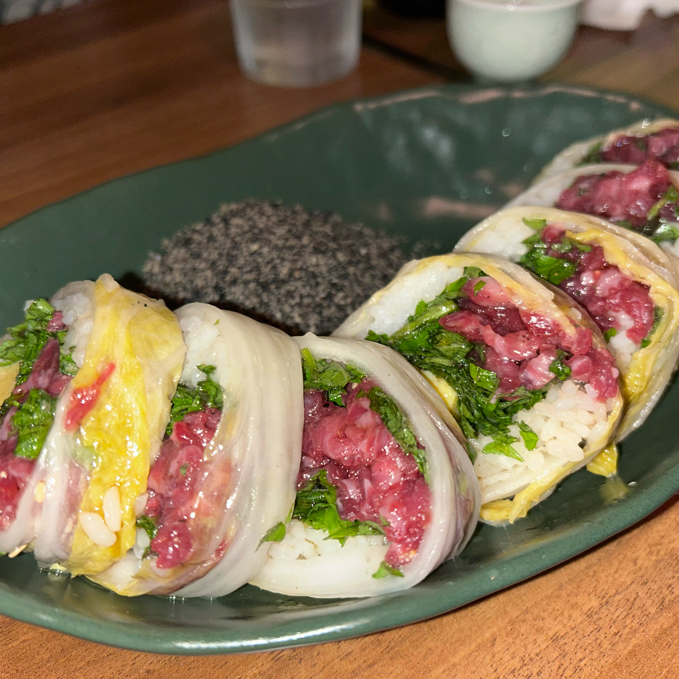 Beef tartare wrapped in fresh napa cabbage leaves on a ceramic plate
