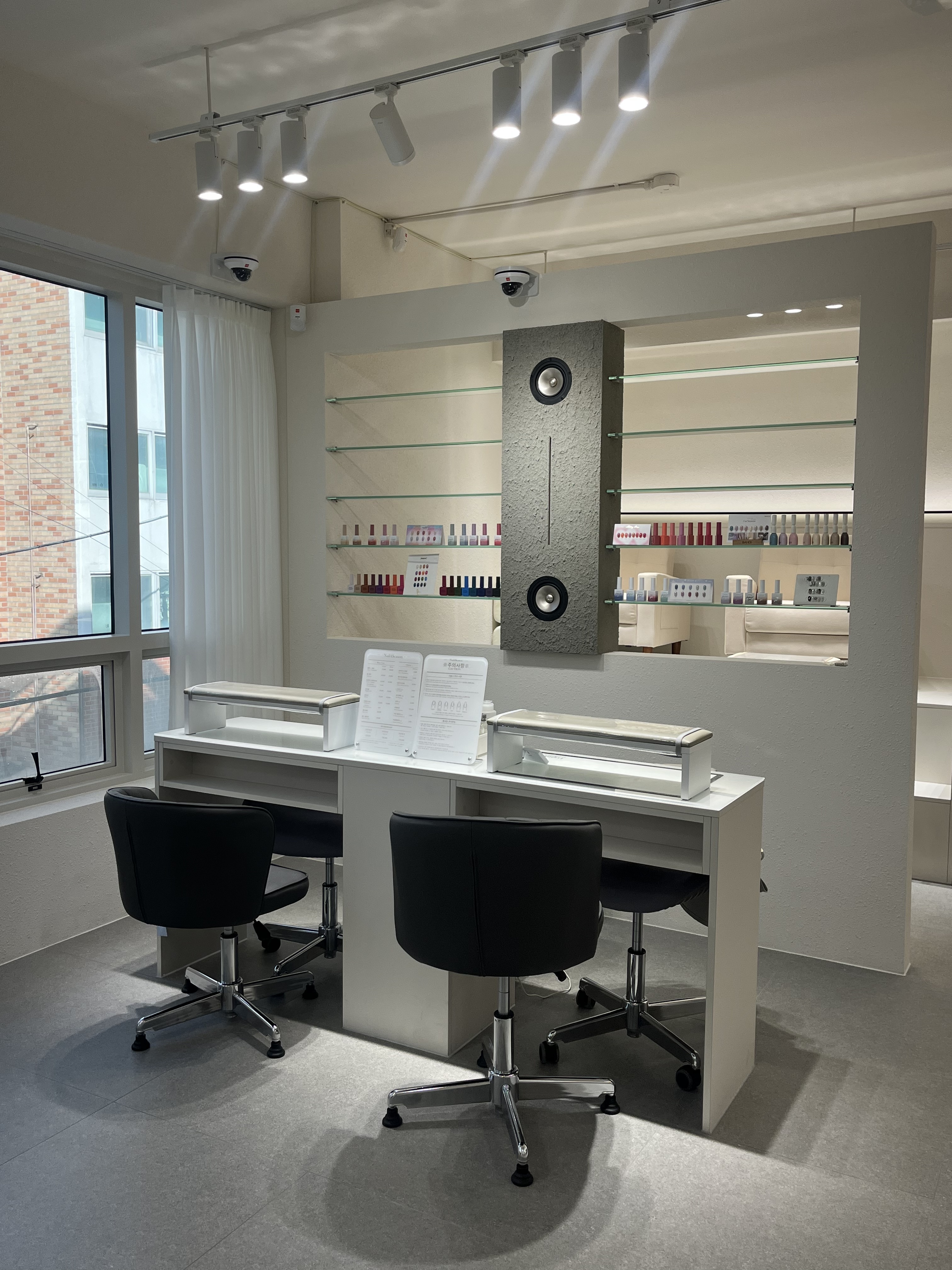 Manicure technician desks with clean ergonomic chairs and recessed polish bottle shelving