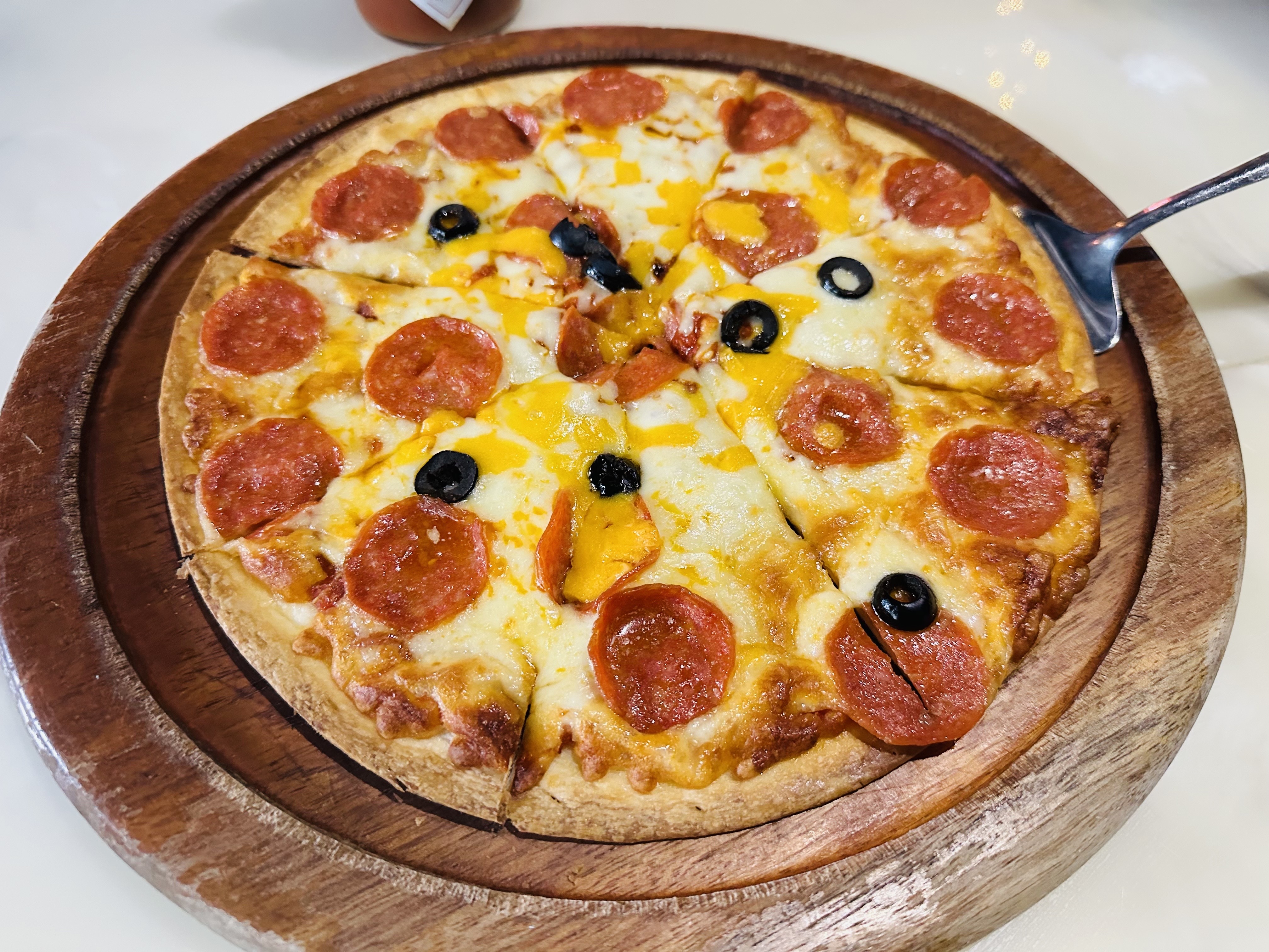 Pepperoni and olive pizza served on wooden board