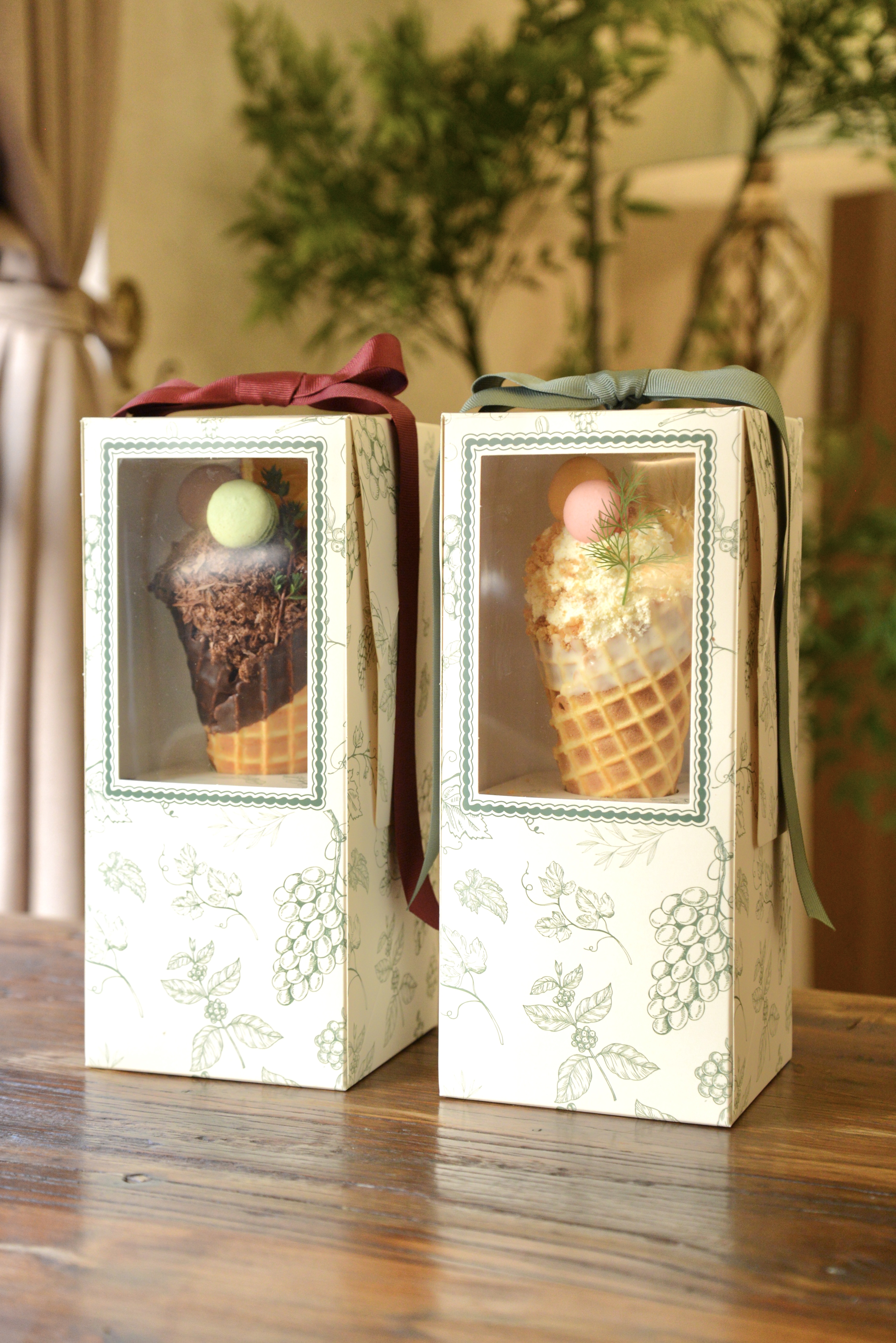 Two decorative gift boxes containing waffle cones placed on a wooden table inside a restaurant.