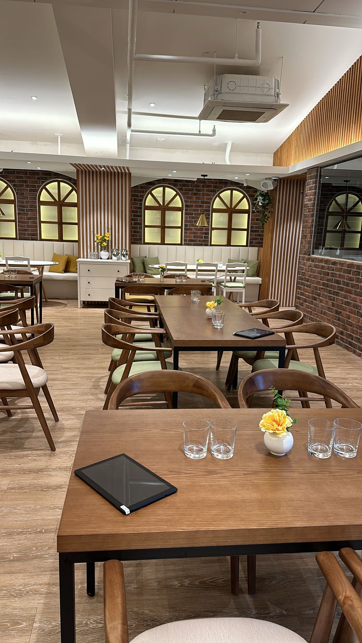Warm and comfortable dining room interior at Saravanaa Bhavan in Itaewon with wooden tables and arched windows