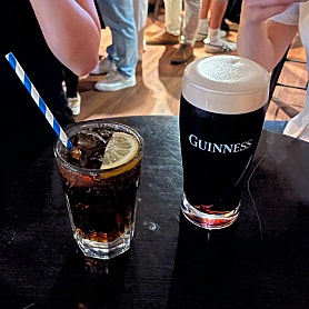 A fresh pint of Guinness Draught stout with thick foam head on a dark table