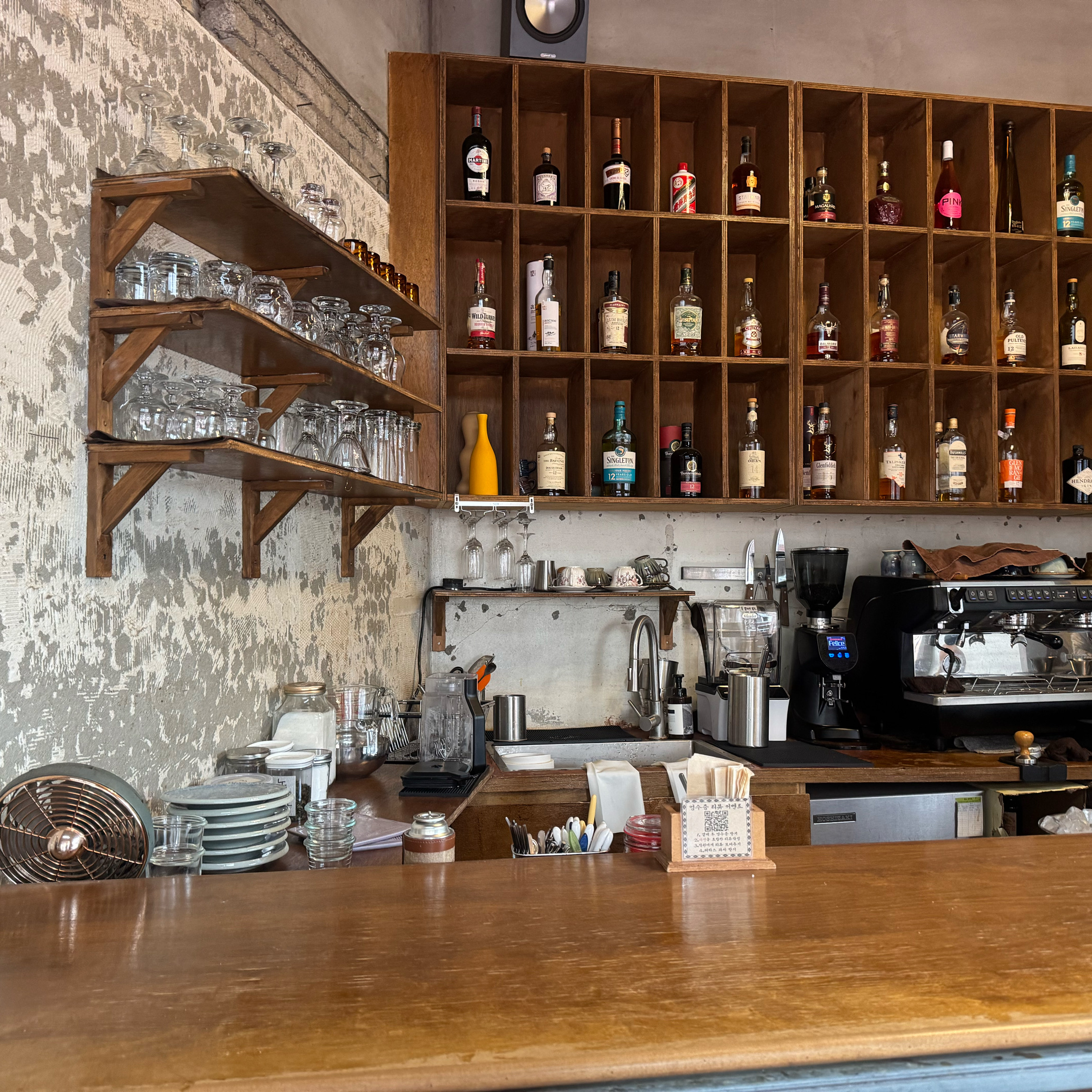 Wooden bar counter with back-bar shelves stocked with Japanese whiskies and spirits