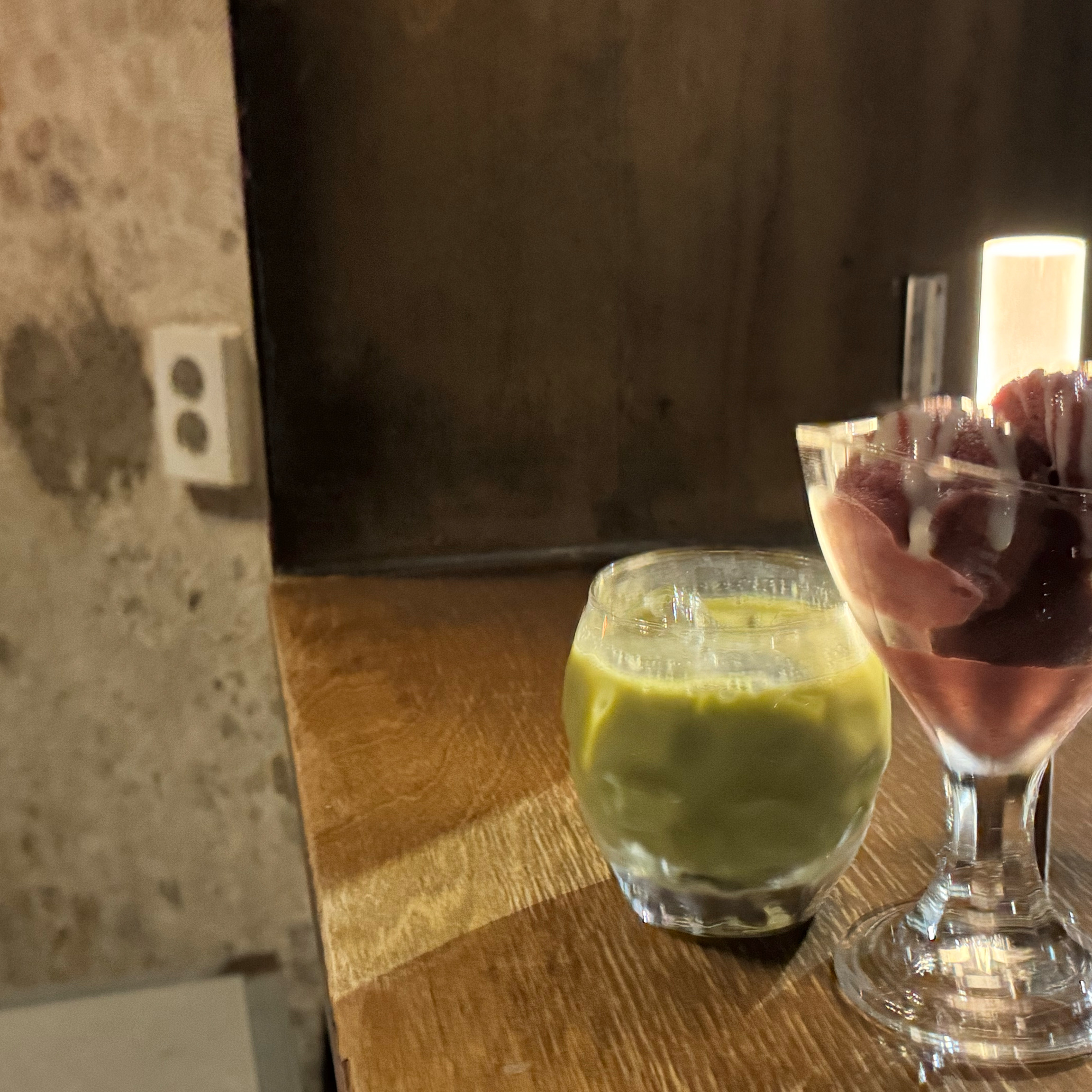 Iced matcha latte and berry dessert on a wooden counter