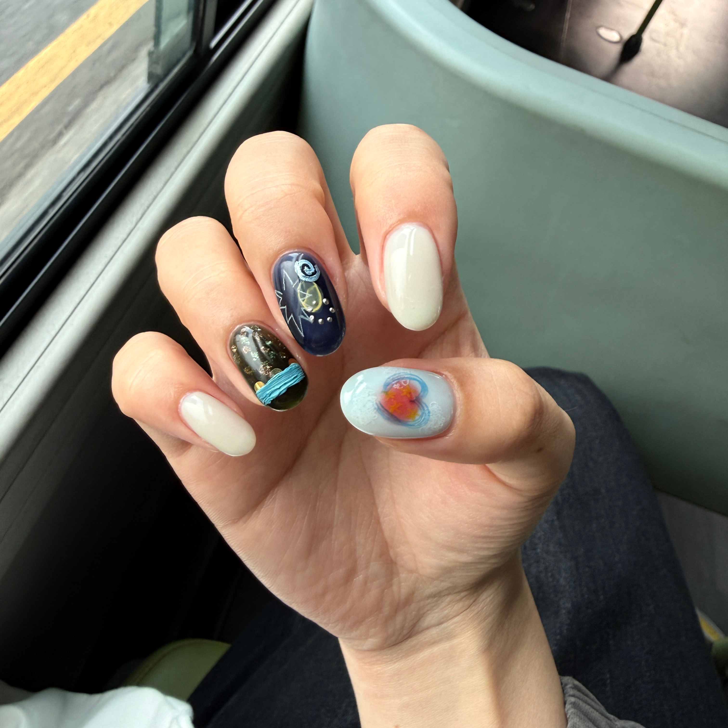 Close-up of hand with artistic nail designs featuring deep navy blue and heart accents