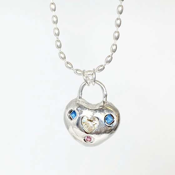 A silver heart-shaped pendant with small blue and pink gemstone accents