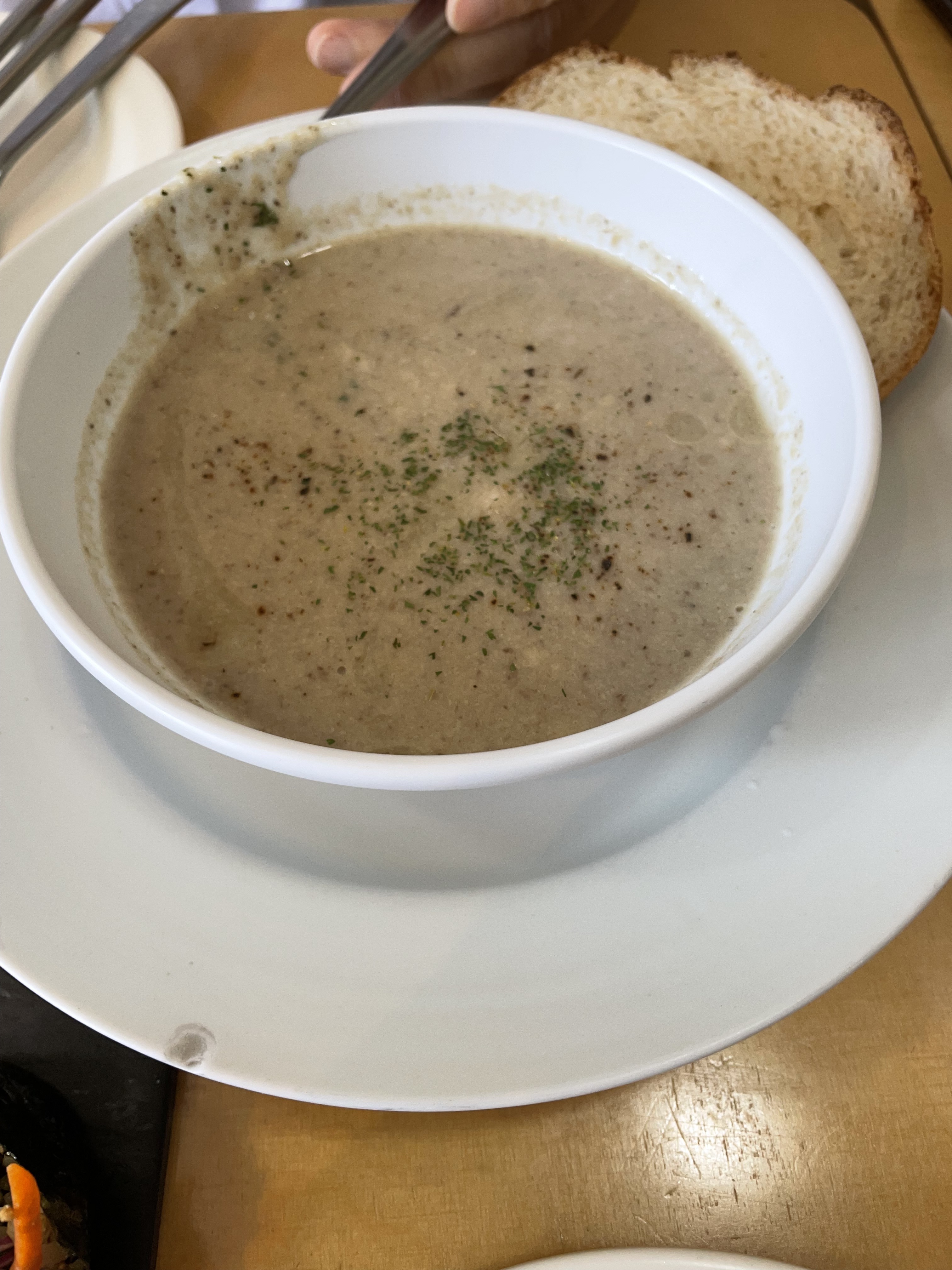 Creamy mushroom soup in a white ceramic bowl served with rustic bread