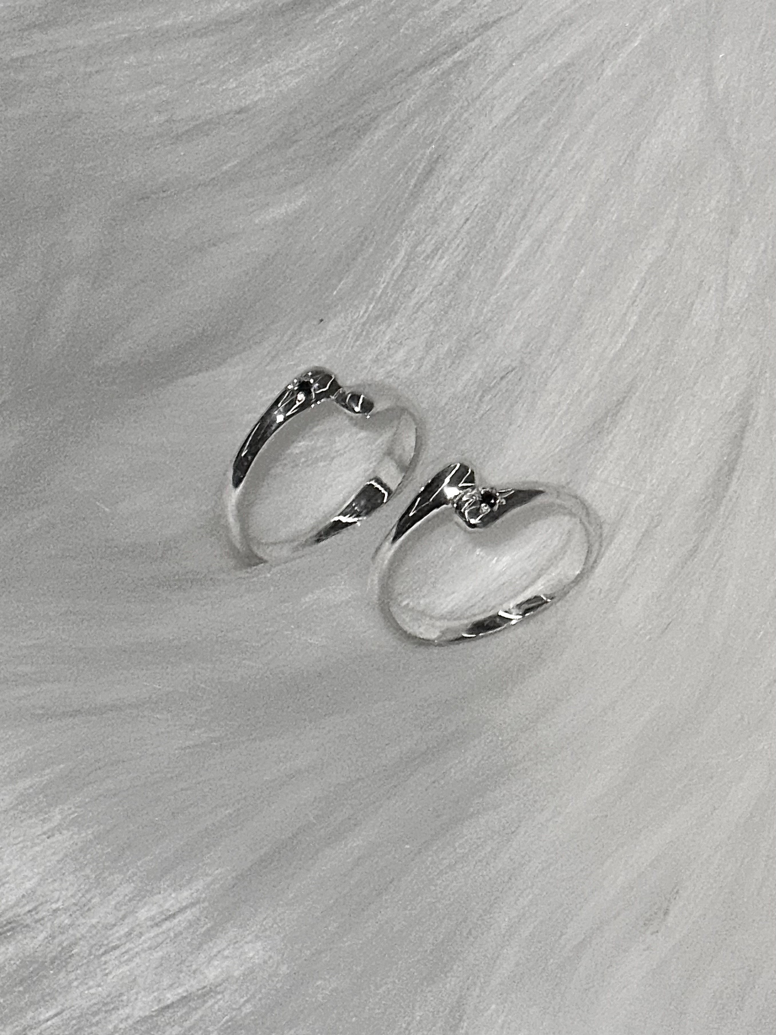 Two silver rings with a decorative knot design resting on a white faux fur surface