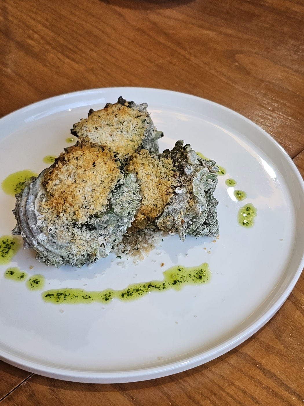Close-up of roasted turban shell appetizer with seasoned crumb topping and herb droplets