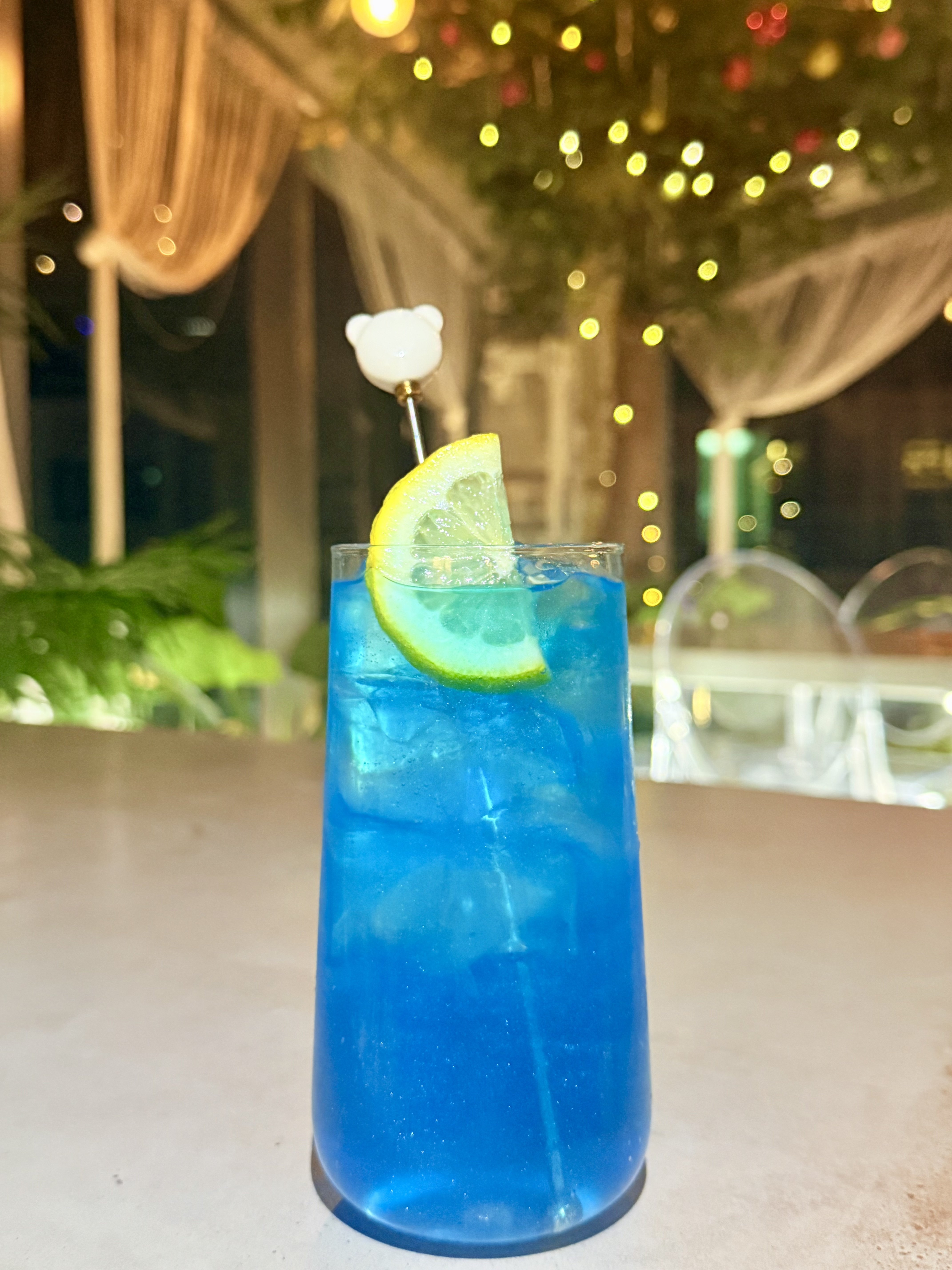 Vibrant blue cocktail in a tall glass with fresh lemon slice garnish
