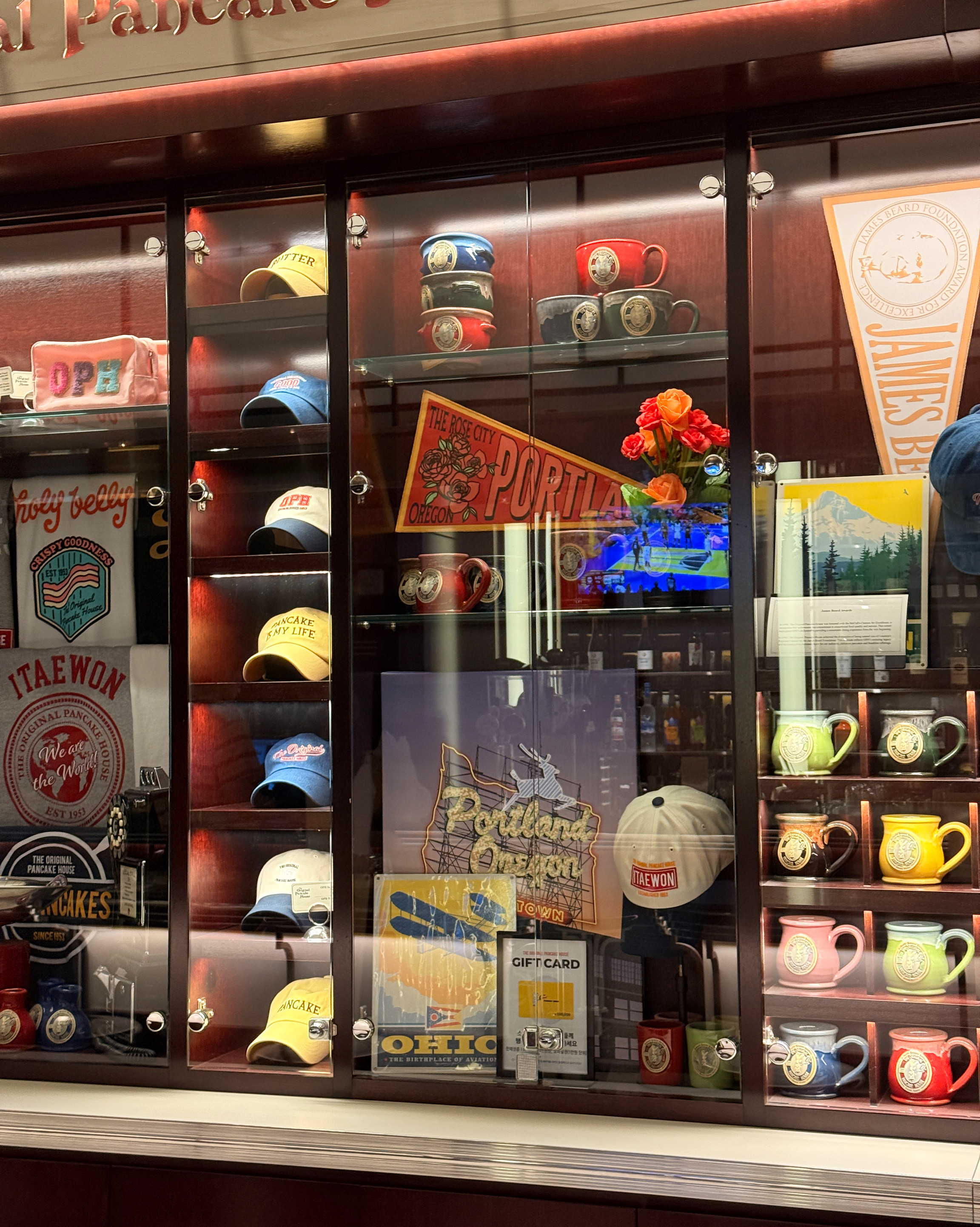 Display cabinet with regional memorabilia, mugs, and branded caps