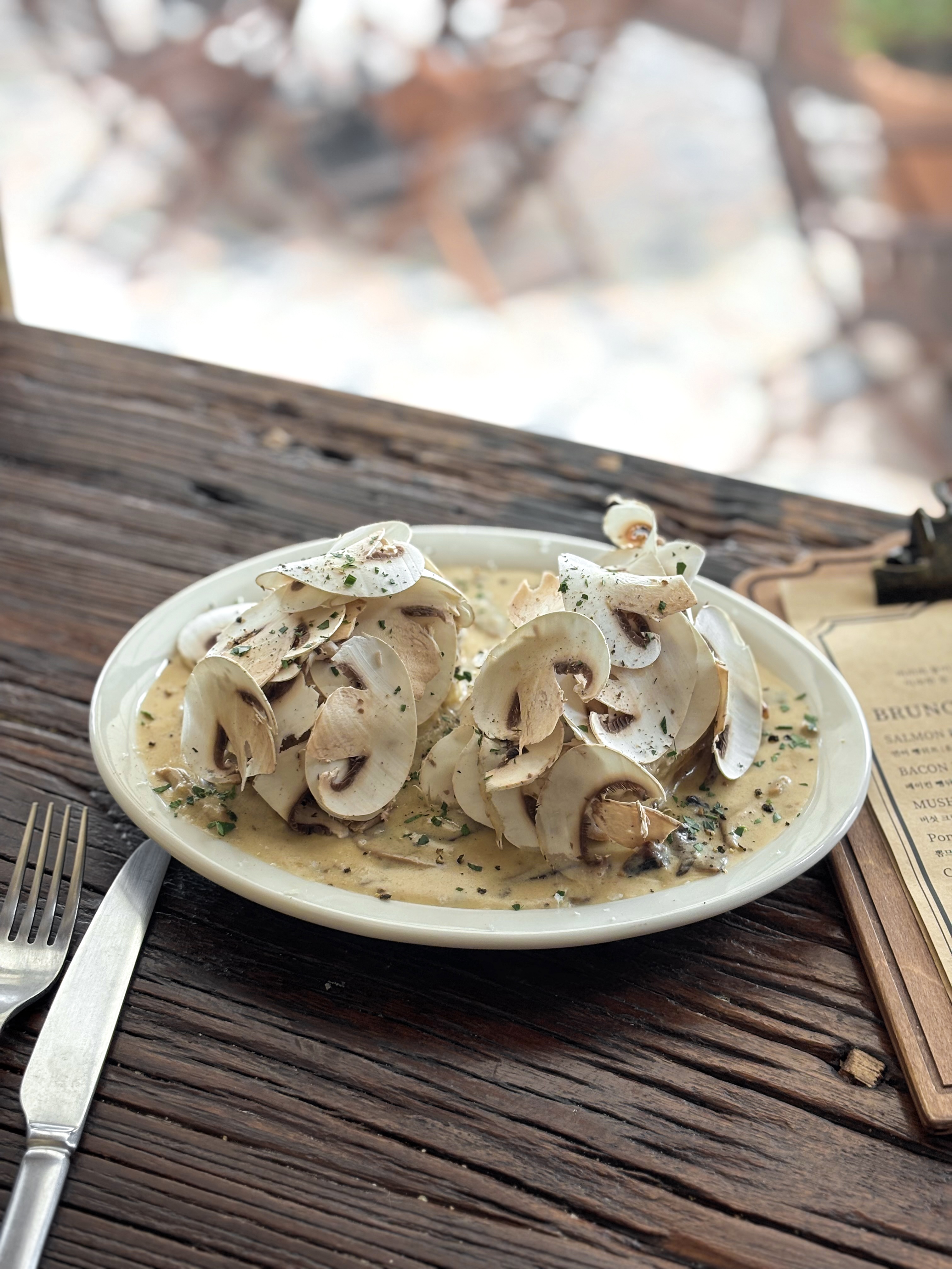 A plate of mushroom cream dish served on a rustic wooden table at a brunch spot.