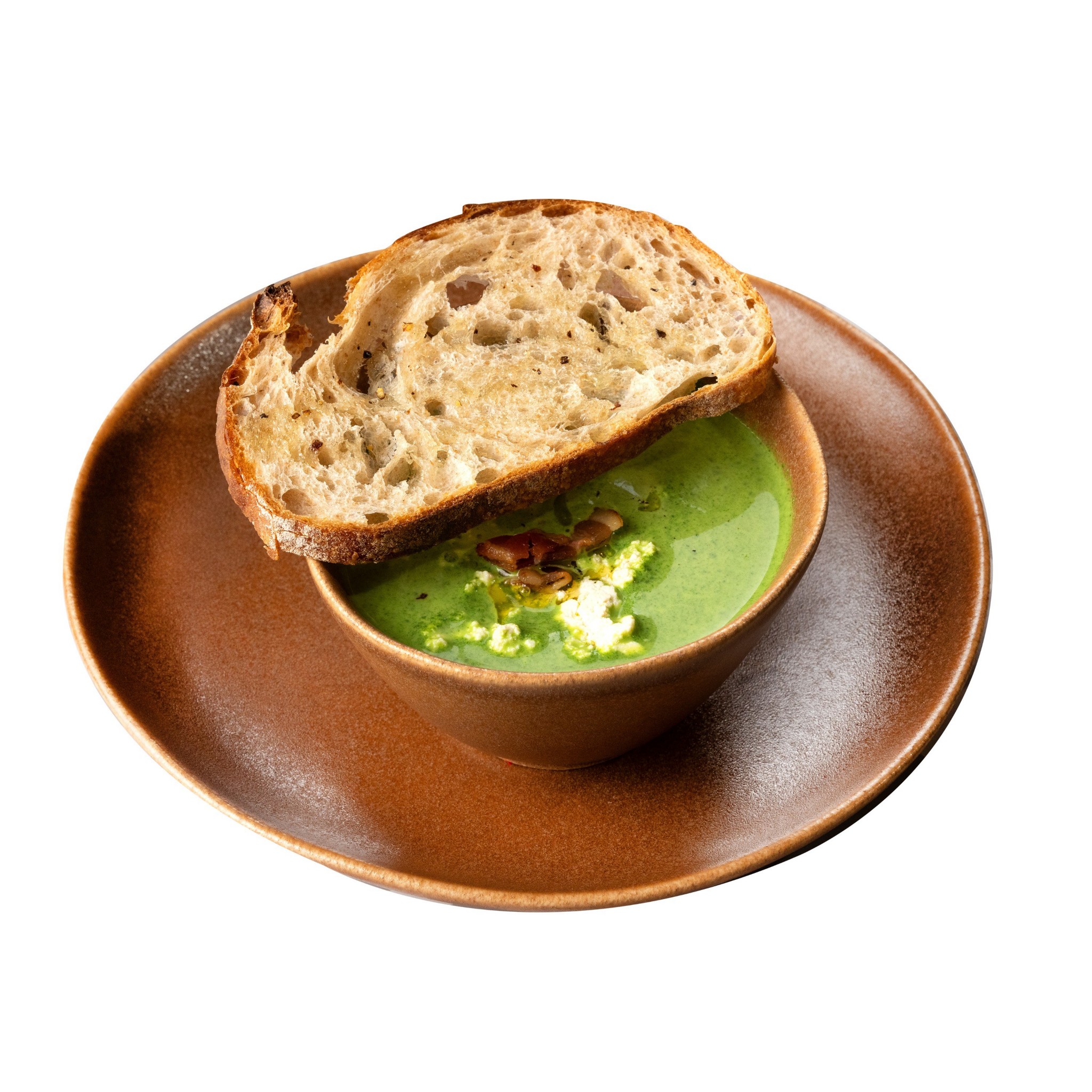 Bowl of vibrant green vegetable soup served with toasted artisan sourdough bread