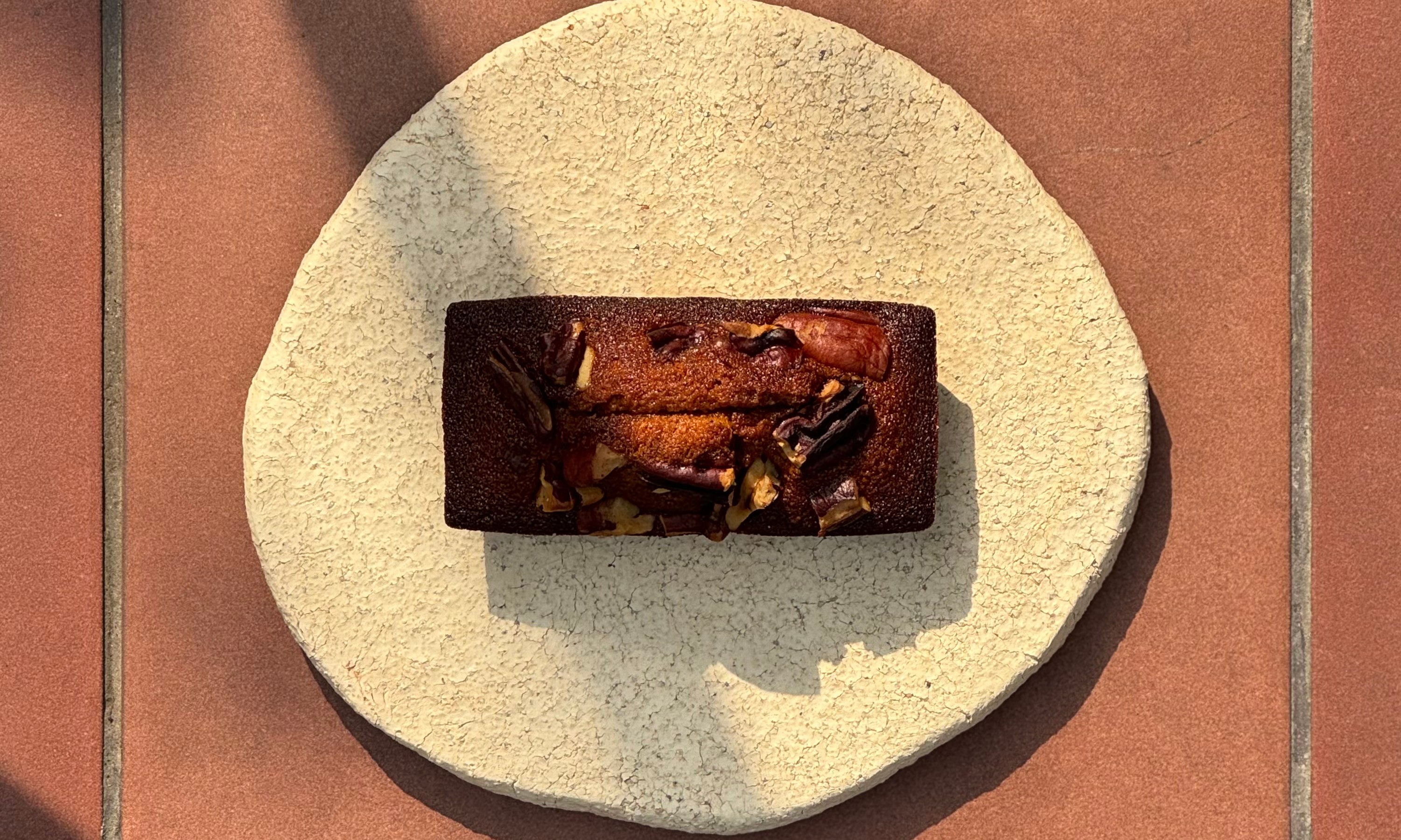Rectangular artisanal nut loaf baked treat on a circular stone ceramic plate