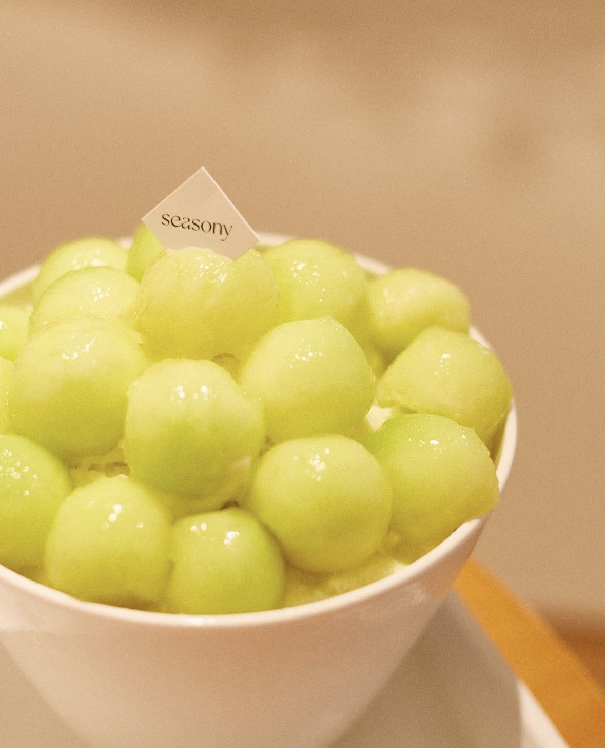 Bowl piled high with fresh light-green melon balls and brand flag