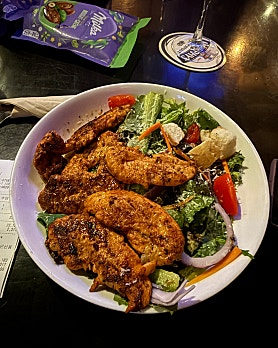 Plate of seasoned grilled chicken salad with croutons, tomatoes, and greens