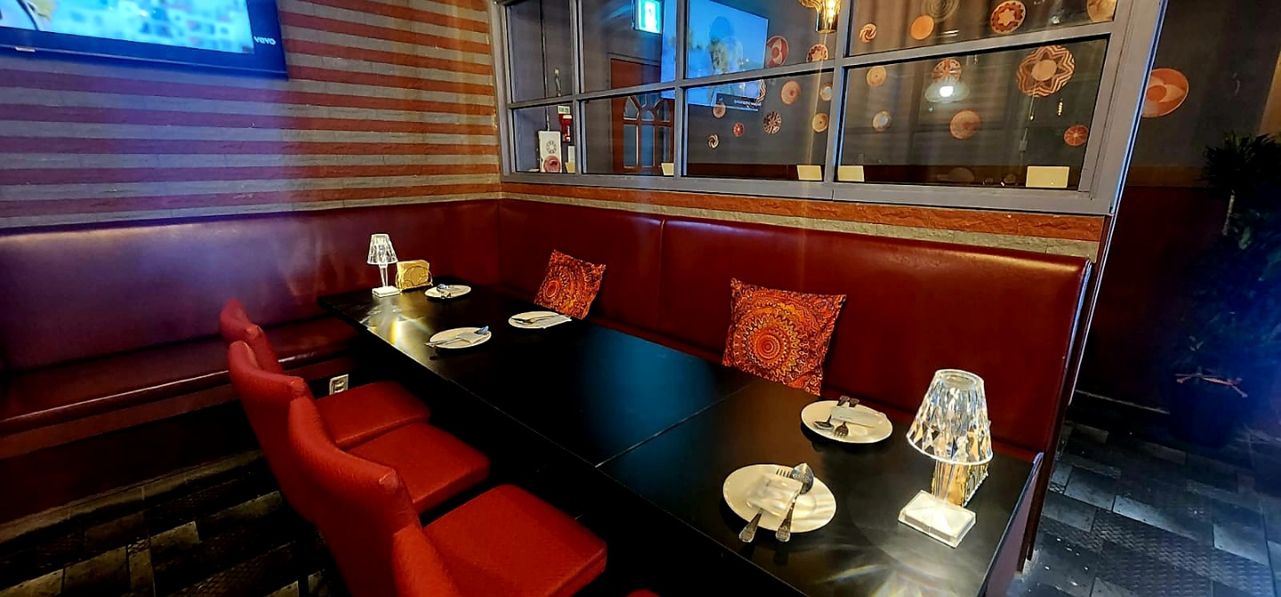 Spacious red leather booth seating area with warm table lamp lighting