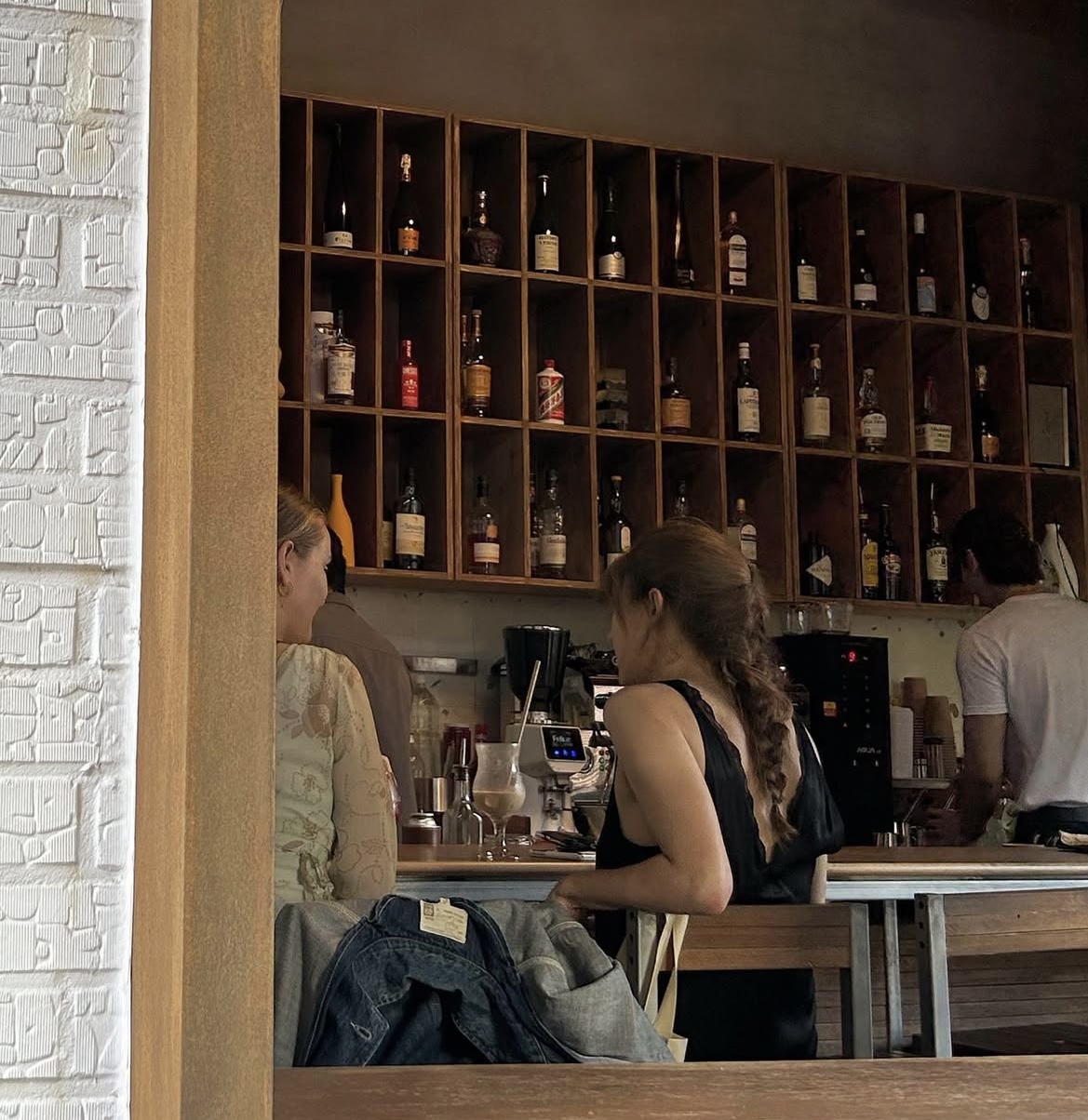 Warm interior view through the doorway showing bottle shelves and counter seating