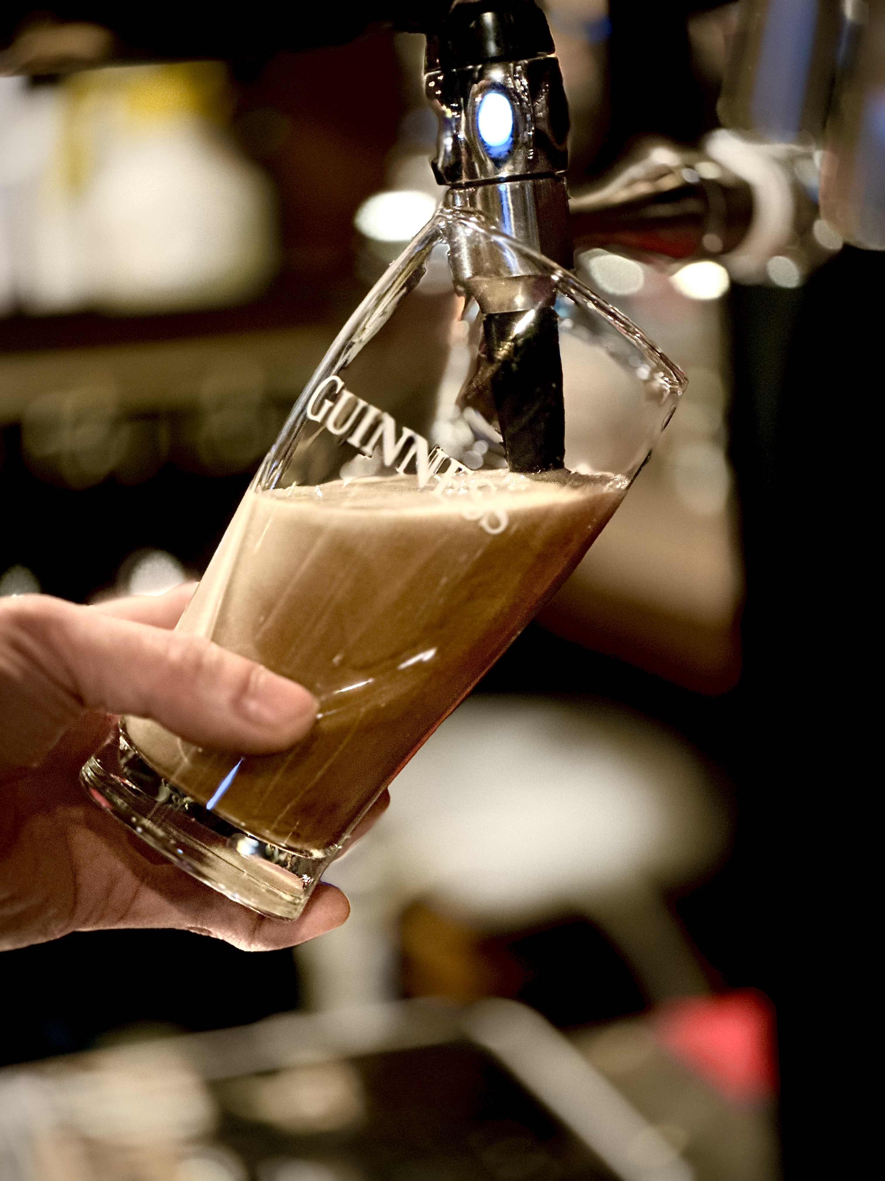 A fresh pour of Guinness beer into a branded glass from the tap