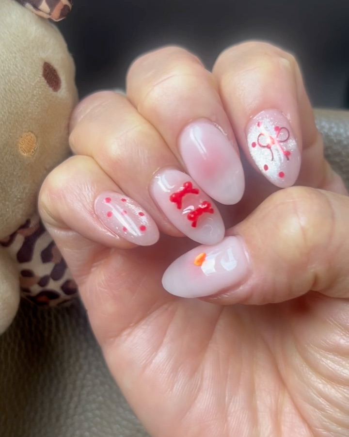Almond manicured nails with soft pink ombre and 3D red ribbon accents