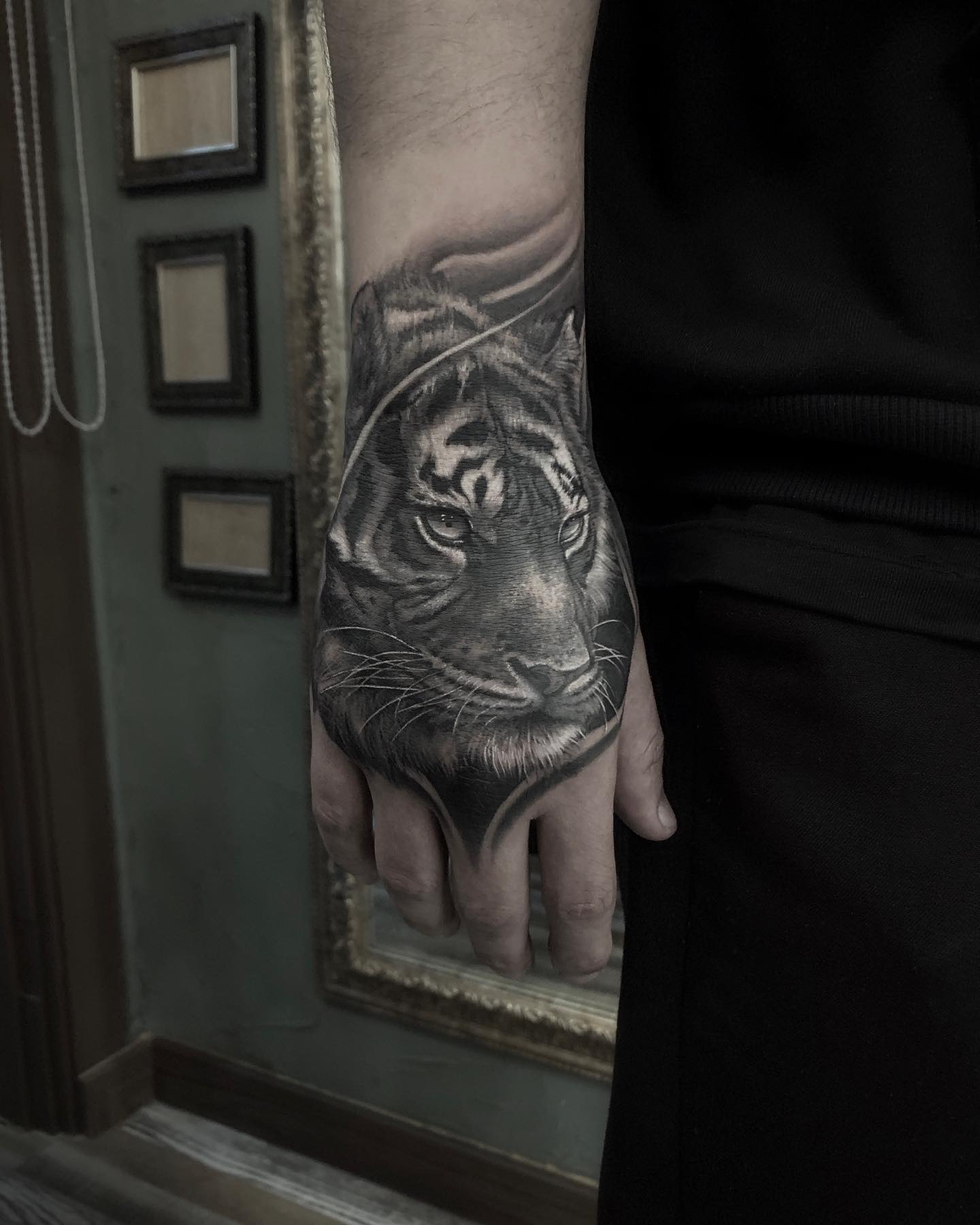 A detailed black and grey tiger tattoo on the back of a person's hand.