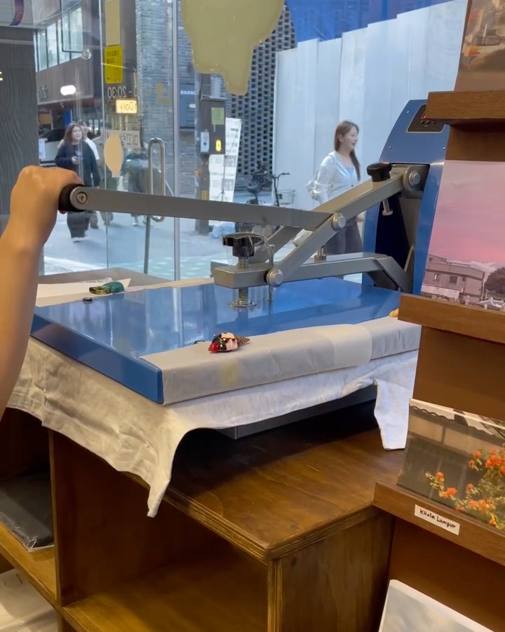 Person operating heat press machine on custom apparel