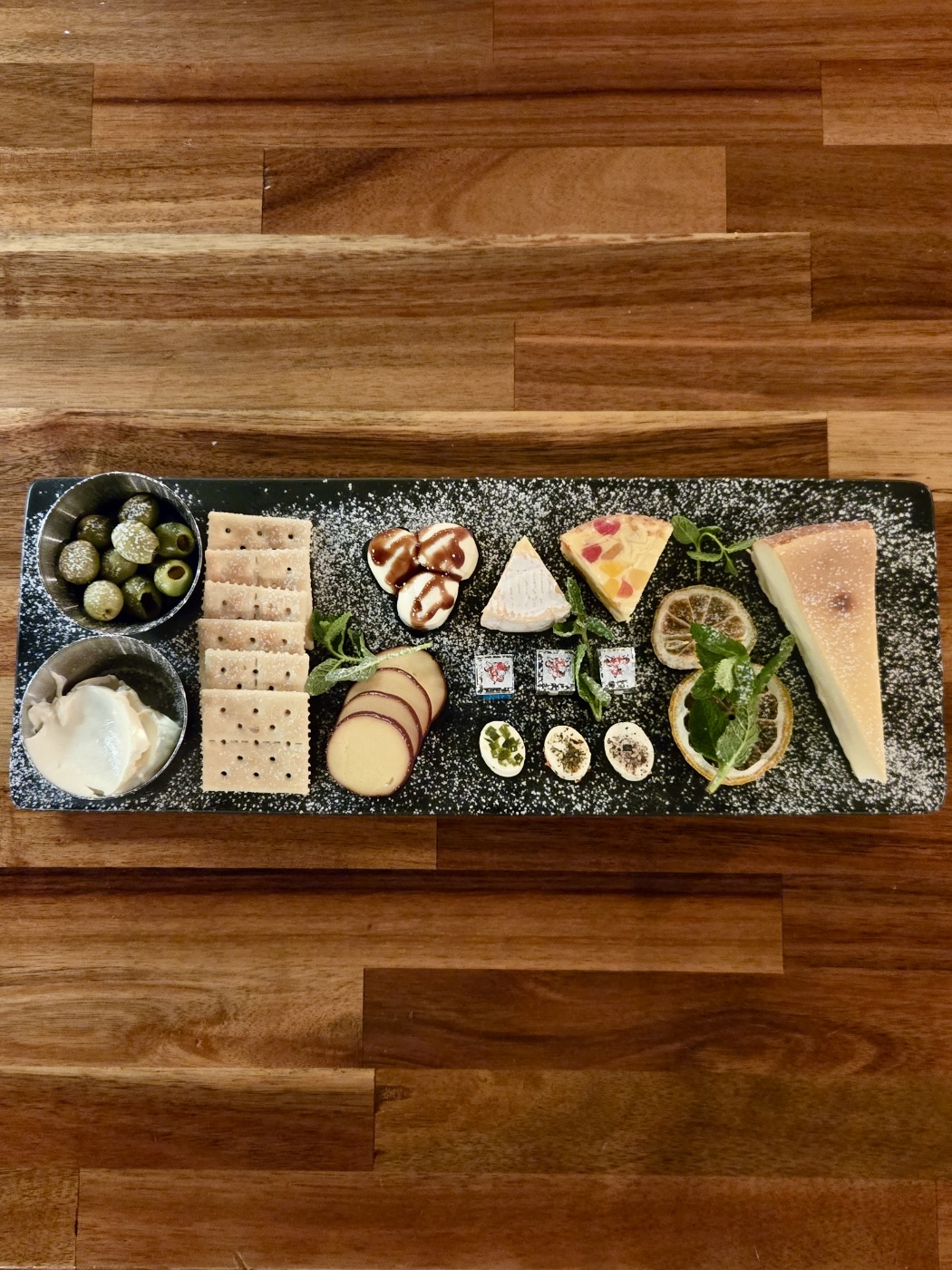 A charcuterie and cheese appetizer board served on a rectangular slate tray