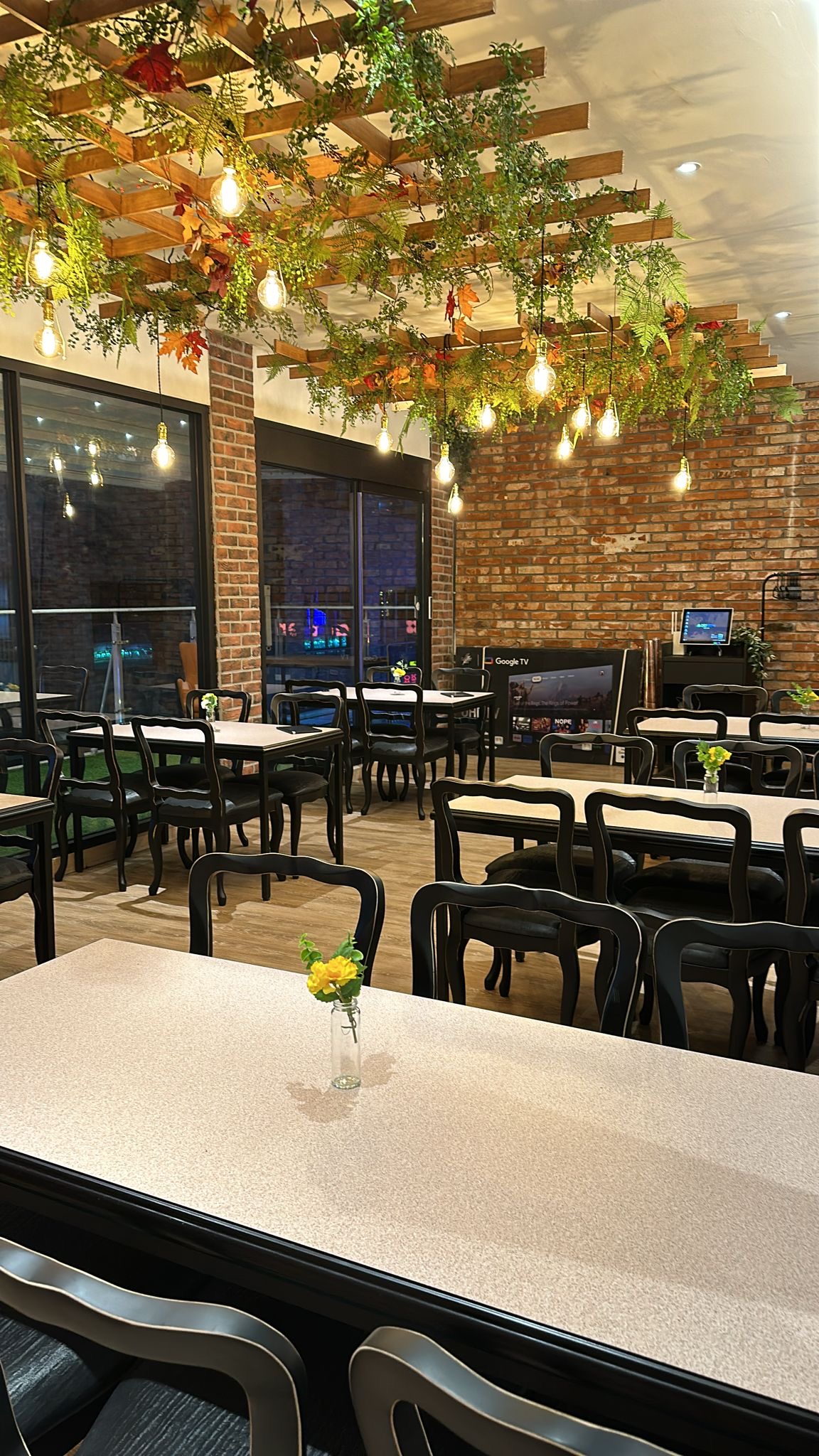 Dining room seating with hanging filament bulbs and wooden ceiling trellis