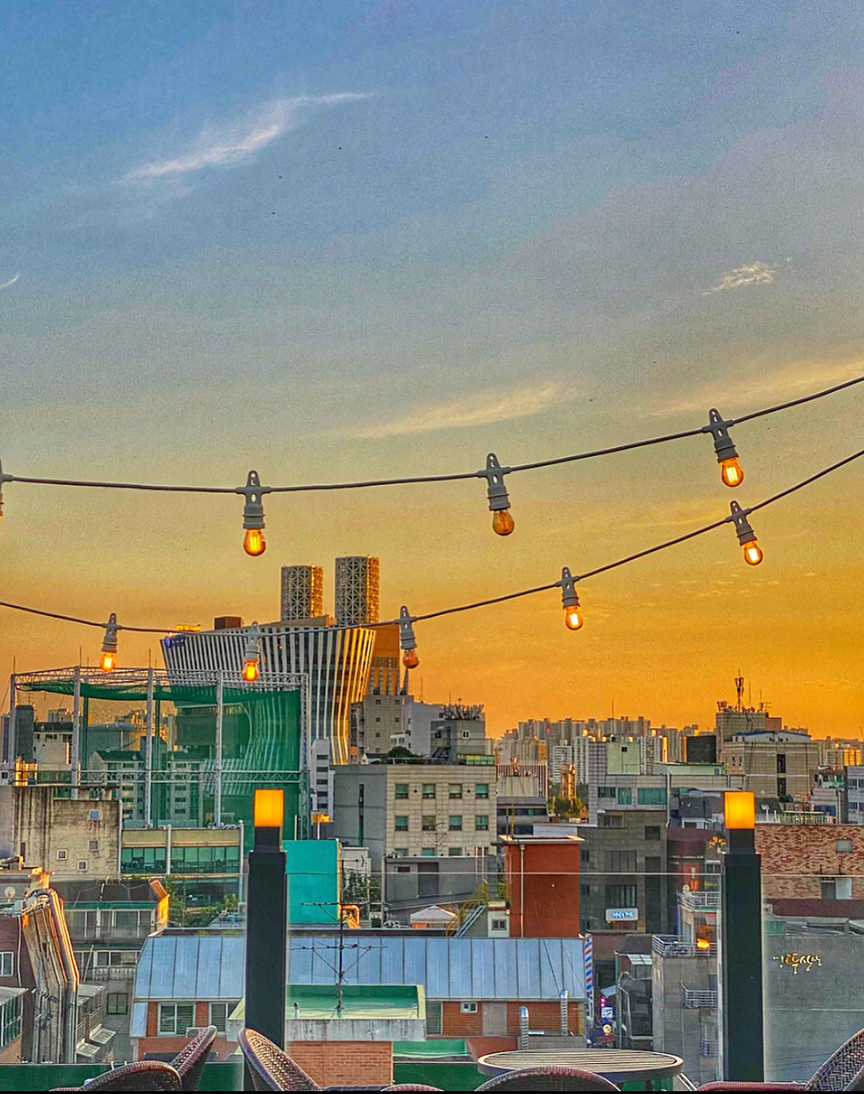Open-air 7th floor rooftop terrace with palm trees and evening views over the Seoul skyline