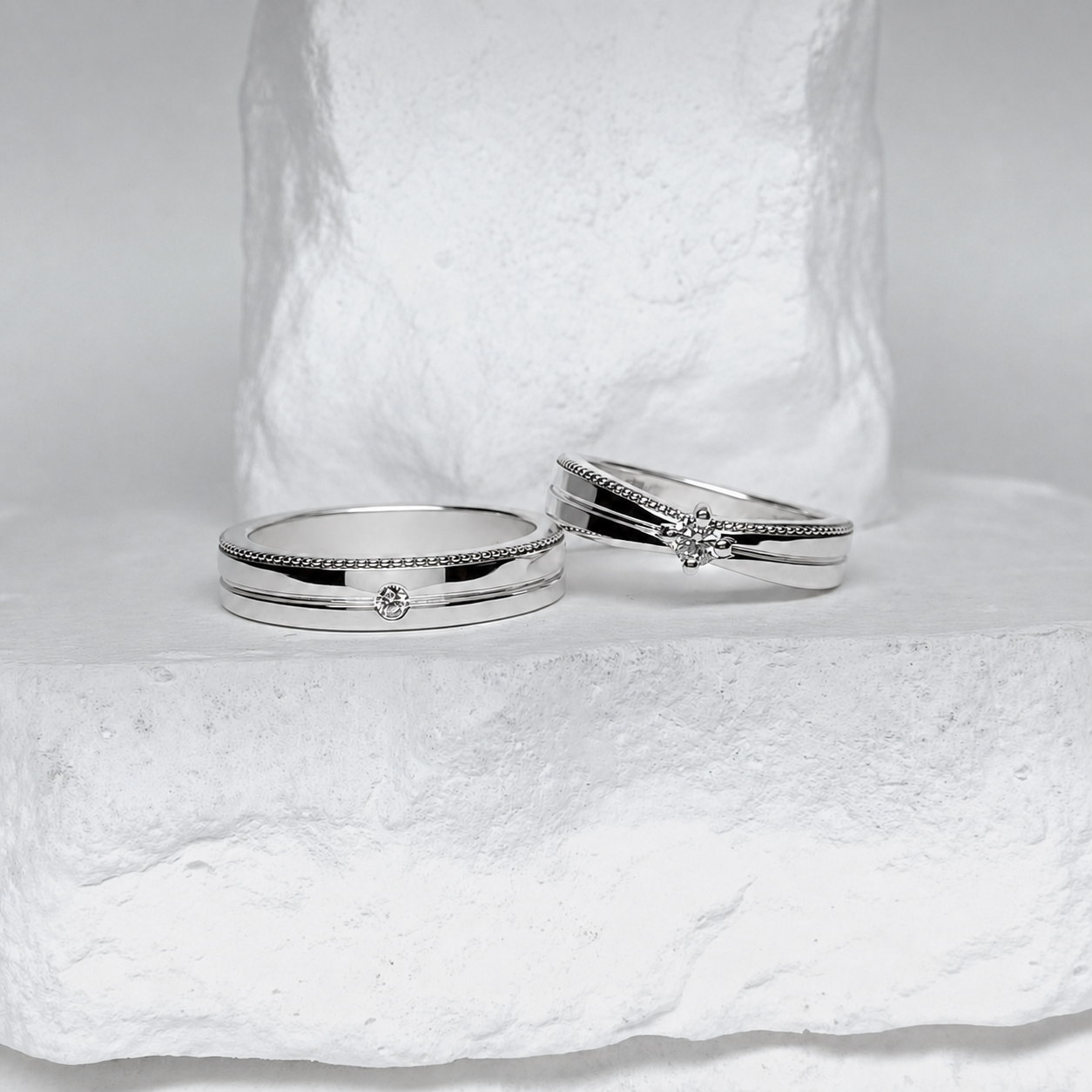 Silver ring pair on a white stone surface