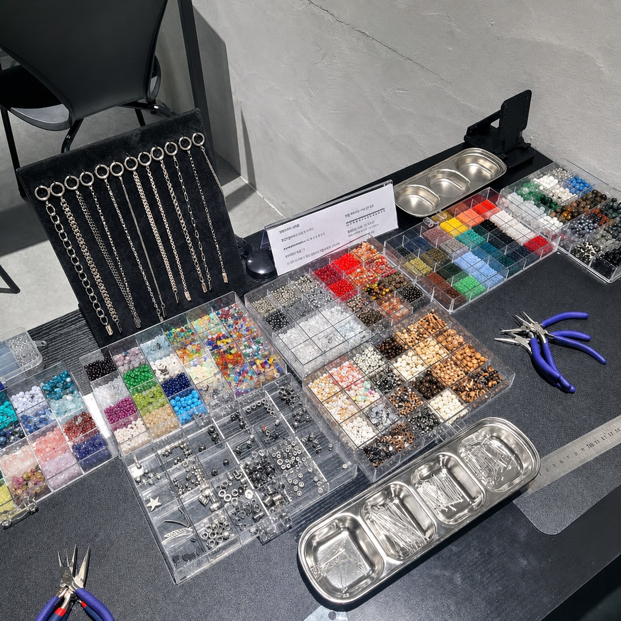 Beads, chains, findings and pliers arranged in workshop trays